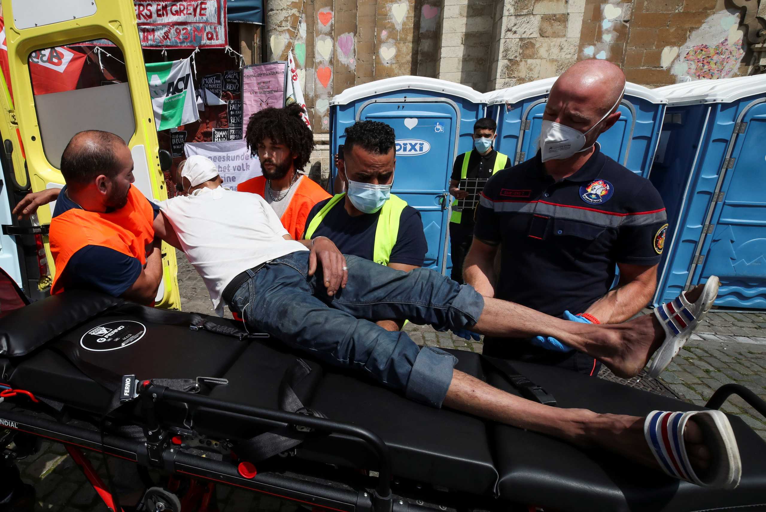An asylum seeker who is among several hundred migrants requesting to be regularised by the Belgian government to have access to healthcare and who has been on hunger strike for more than 7 weeks is transported to an ambulance outside the Saint-Jean-Baptiste au Beguinage church, in Brussels, Belgium, July 19, 2021. REUTERS