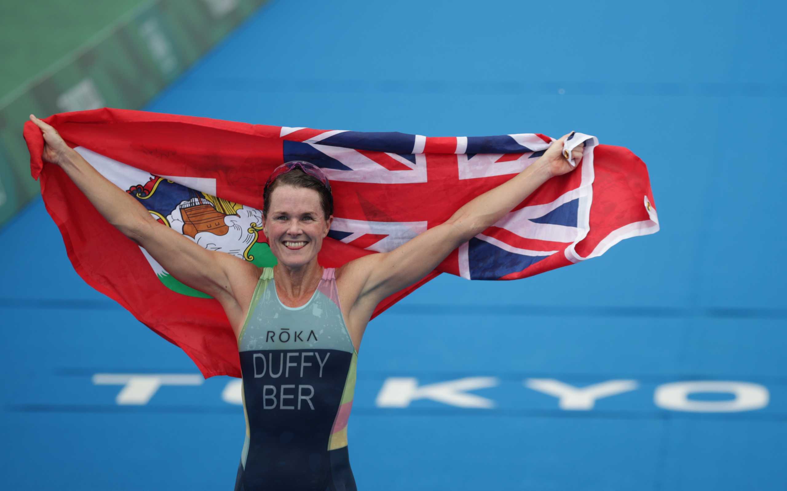 Tokyo 2020 Olympics - Triathlon - Women's Olympic Distance - Final - Odaiba Marine Park, Tokyo, Japan July 27, 2021. Flora Duffy of Bermuda holds national flag as she celebrates victory. REUTERS