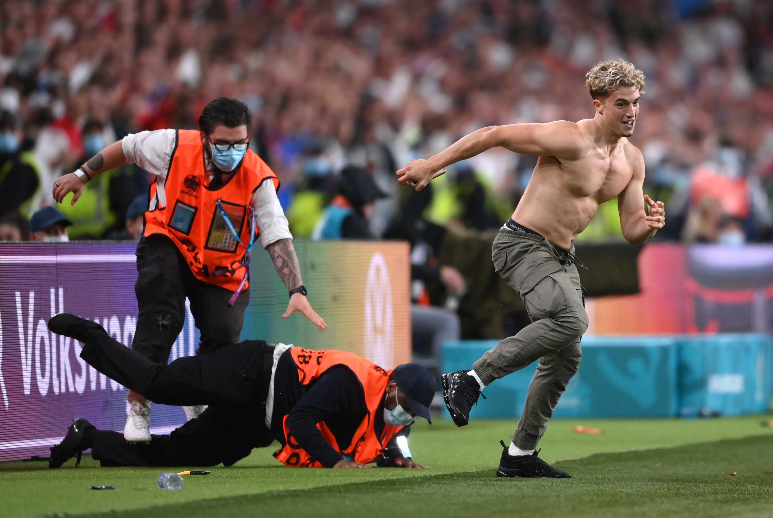 Soccer Football - Euro 2020 - Final - Italy v England - Wembley Stadium, London, Britain - July 11, 2021 Fan invades the pitch during the match as stewards attempt to tackle him Pool via REUTERS