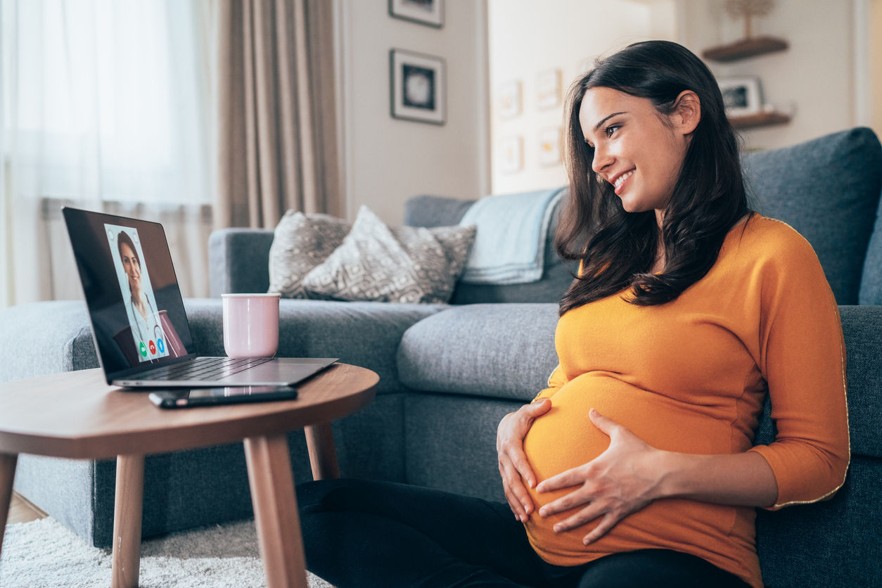 Young beautiful Pregnant woman having Video call with doctor using laptop at home