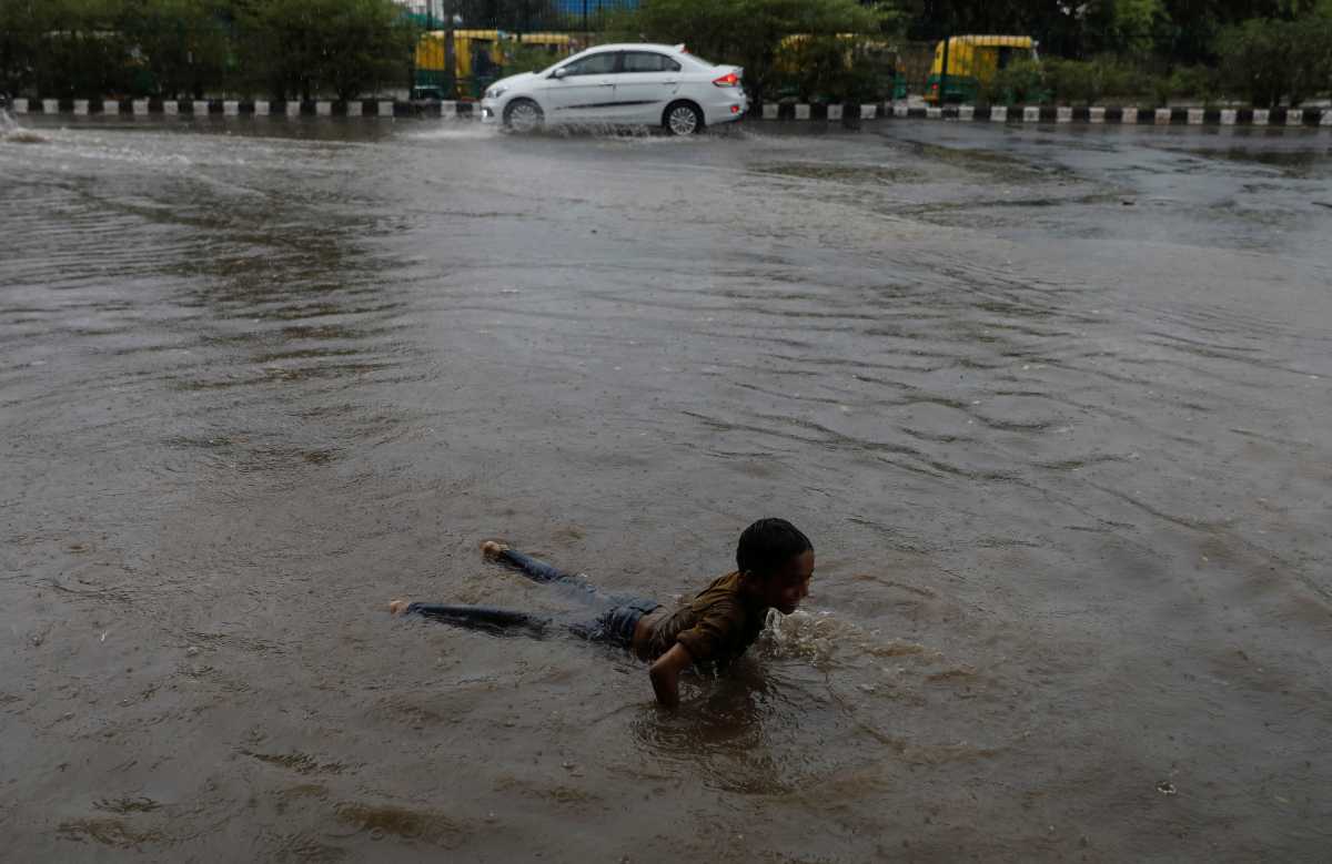 A boy plays on a flooded street after heavy rains in New Delhi, India, July 14, 2021. REUTERS