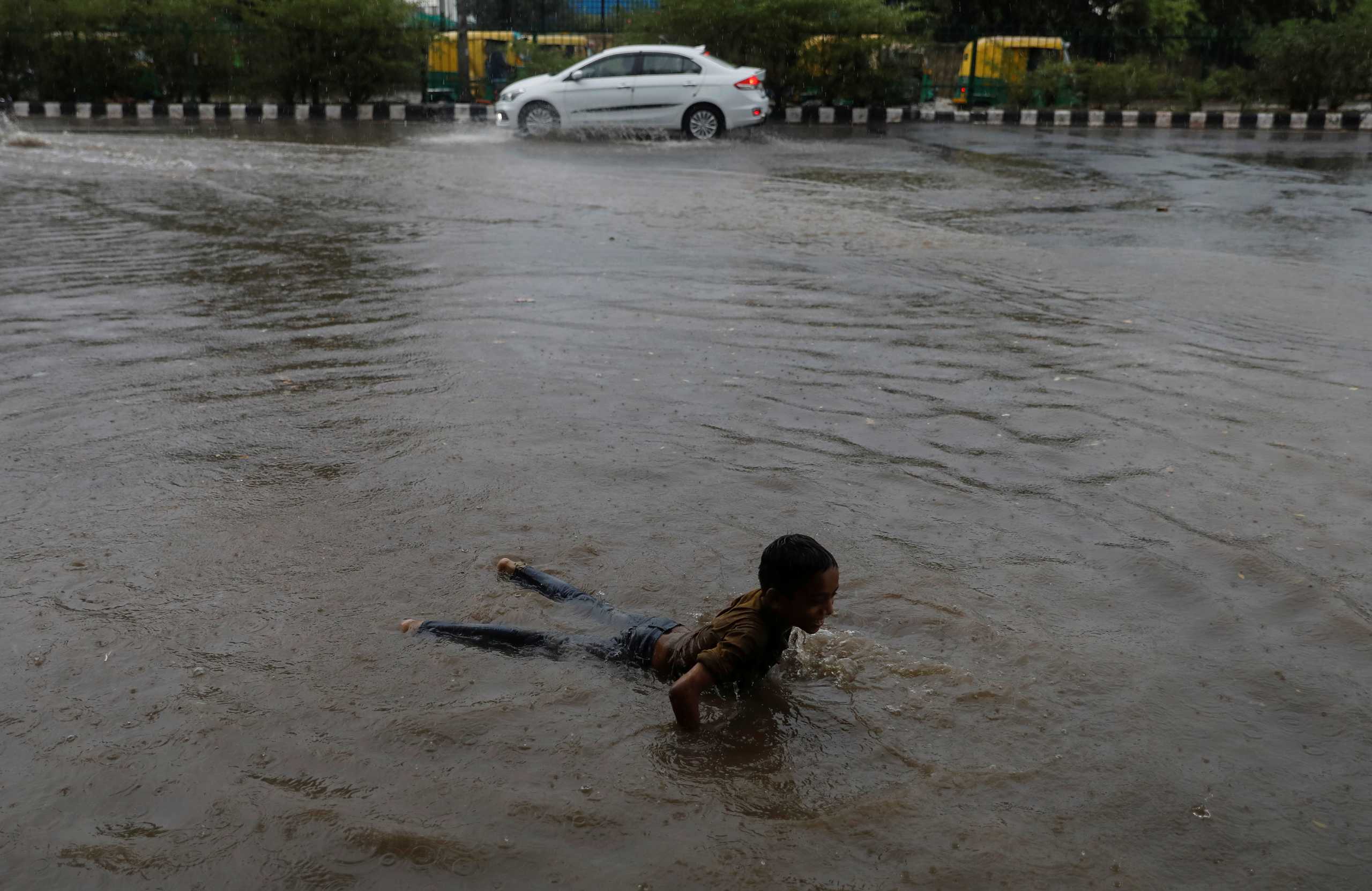 A boy plays on a flooded street after heavy rains in New Delhi, India, July 14, 2021. REUTERS