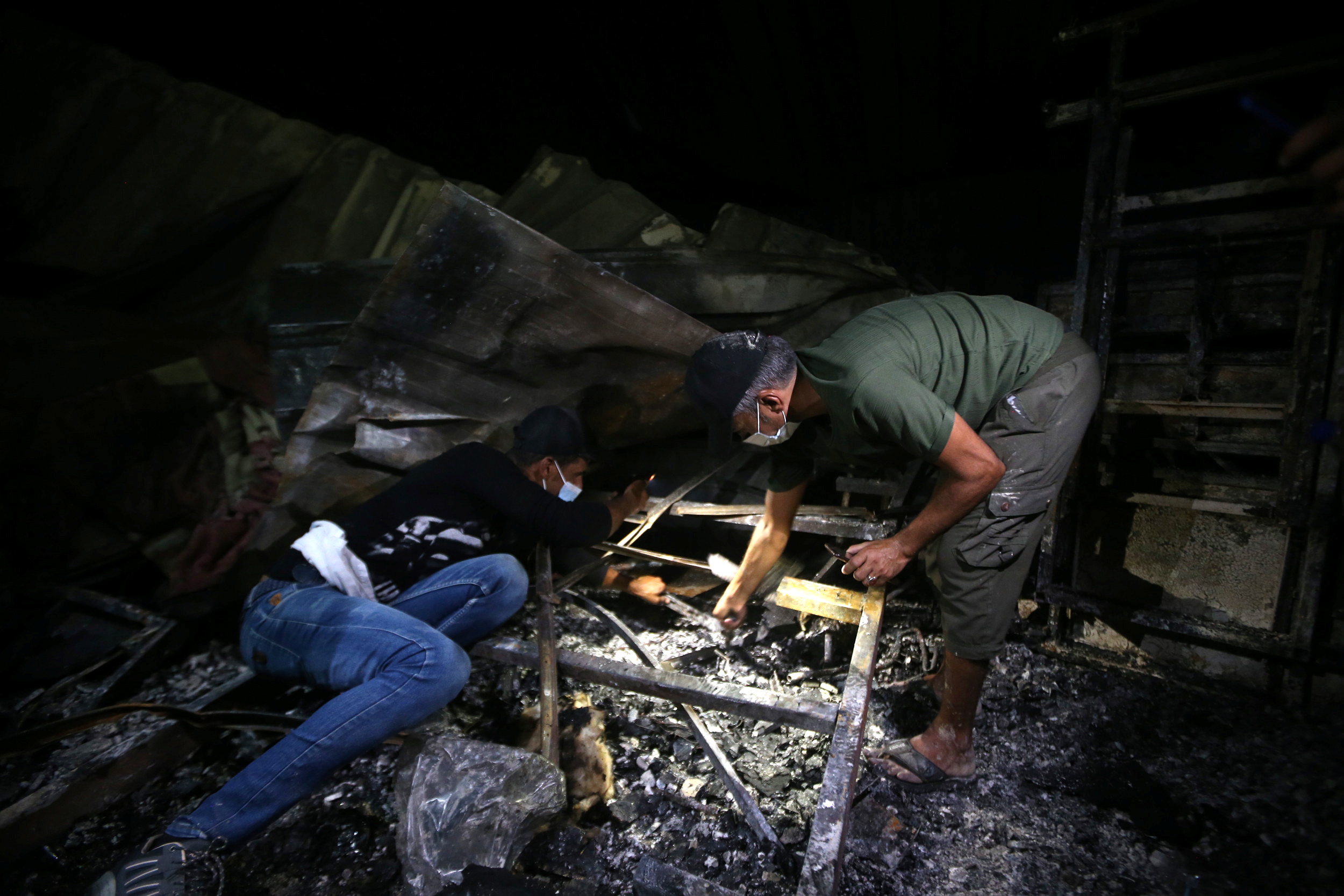 People inspect the damage at the site where a fire broke out at al-Hussain coronavirus hospital, in Nassiriya, Iraq, July 13, 2021. REUTERS