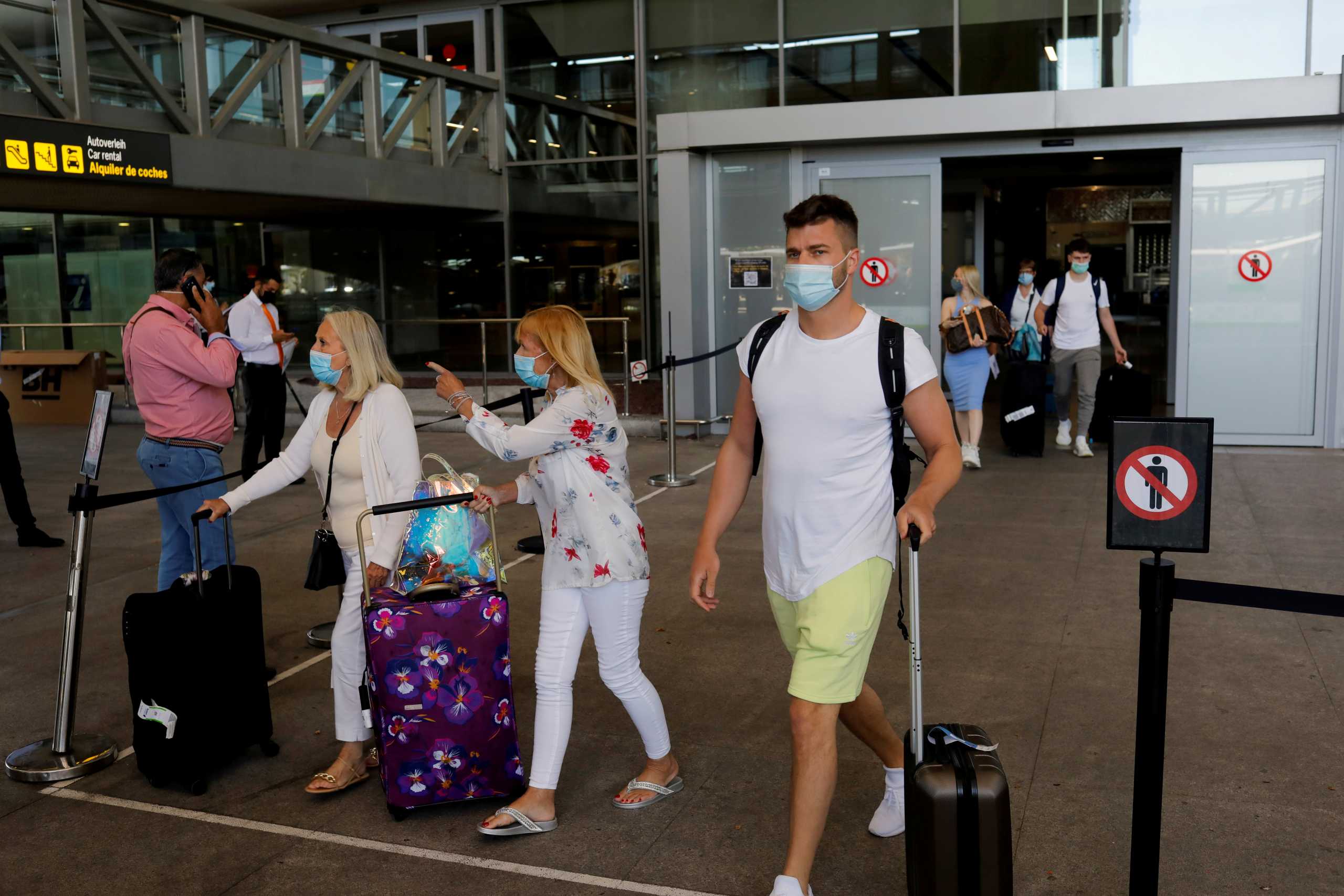 FILE PHOTO: Tourists wearing protective face masks walk with their luggage as they arrive at Malaga-Costa del Sol Airport, in Malaga, Spain, June 7, 2021. REUTERS