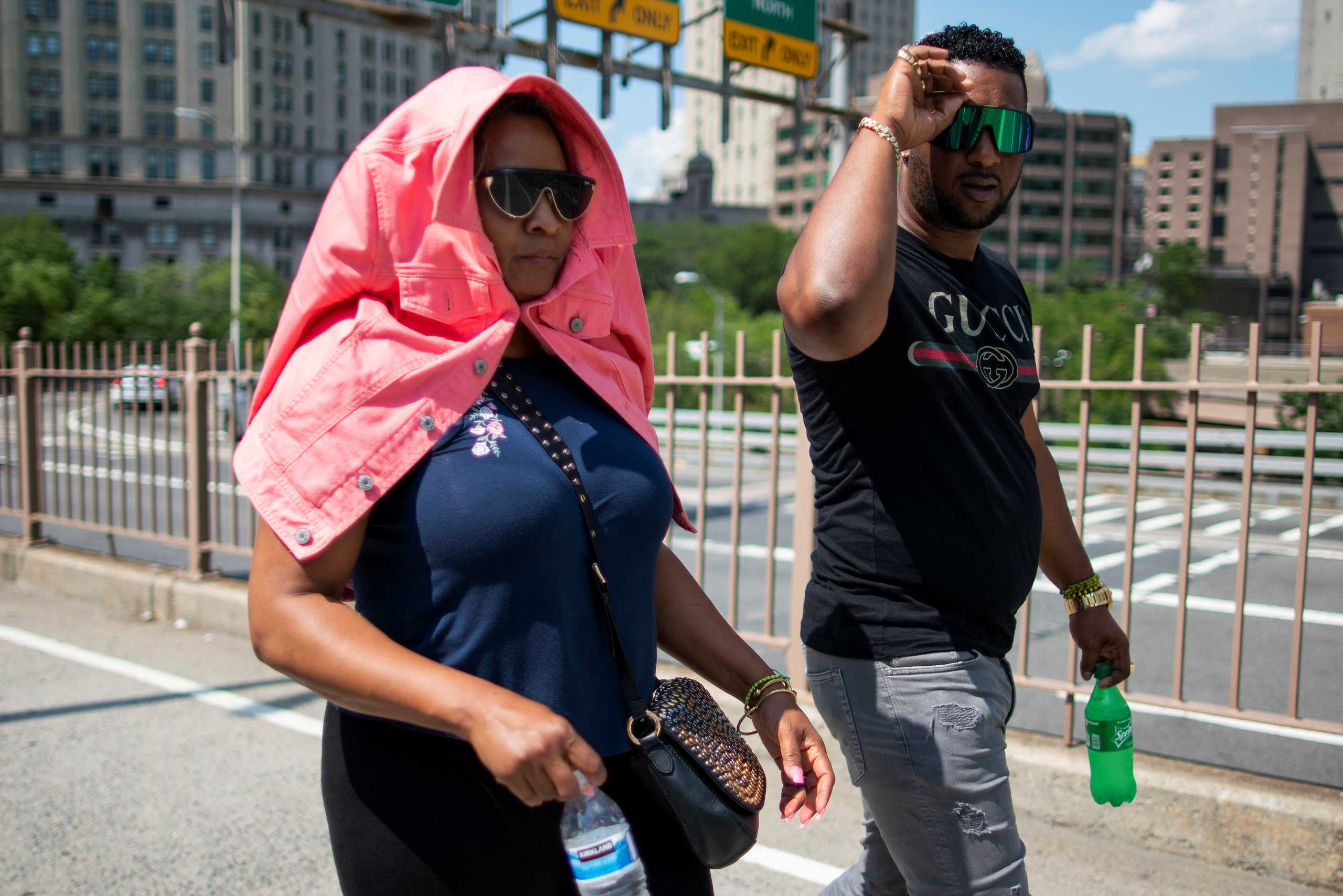 A woman covering herself from the sun walks during a heat wave at the Brooklyn Bridge in New York, U.S., June 30, 2021.  REUTERS