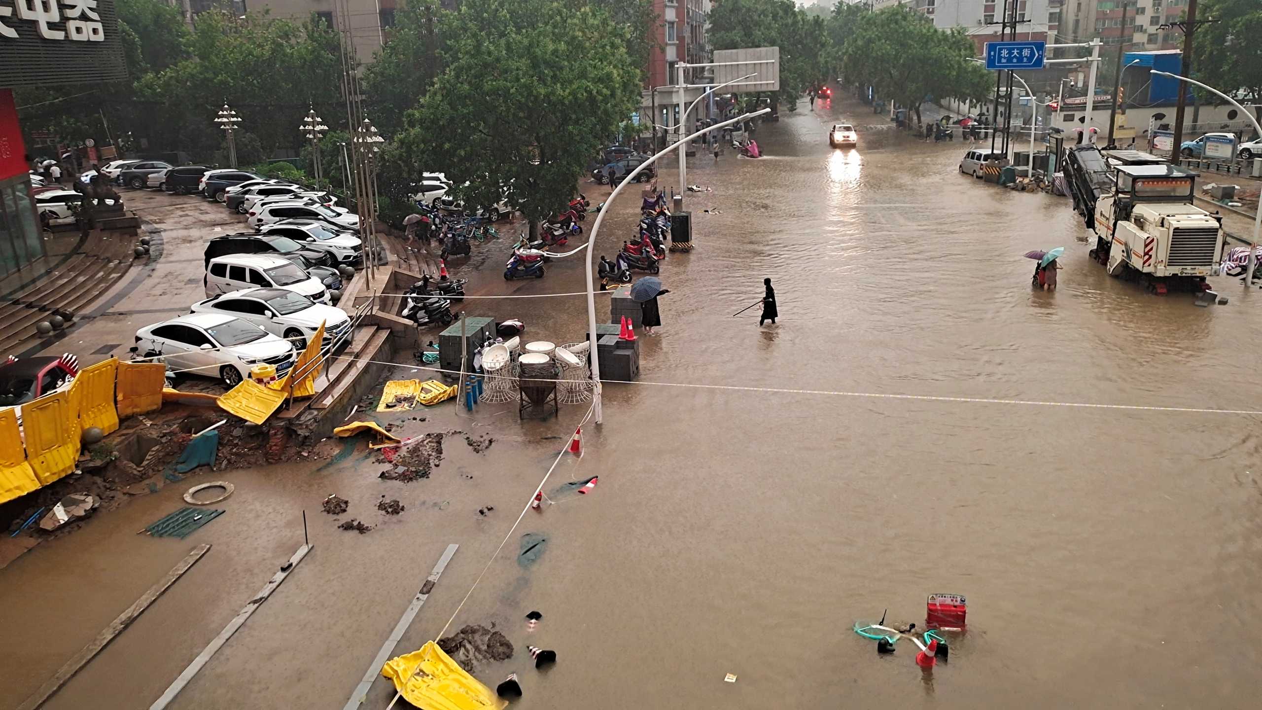 People wade through floodwaters on a road amid heavy rainfall in Zhengzhou, Henan province, China July 20, 2021. Picture taken July 20, 2021. China Daily via REUTERS  ATTENTION EDITORS - THIS IMAGE WAS PROVIDED BY A THIRD PARTY. CHINA OUT.