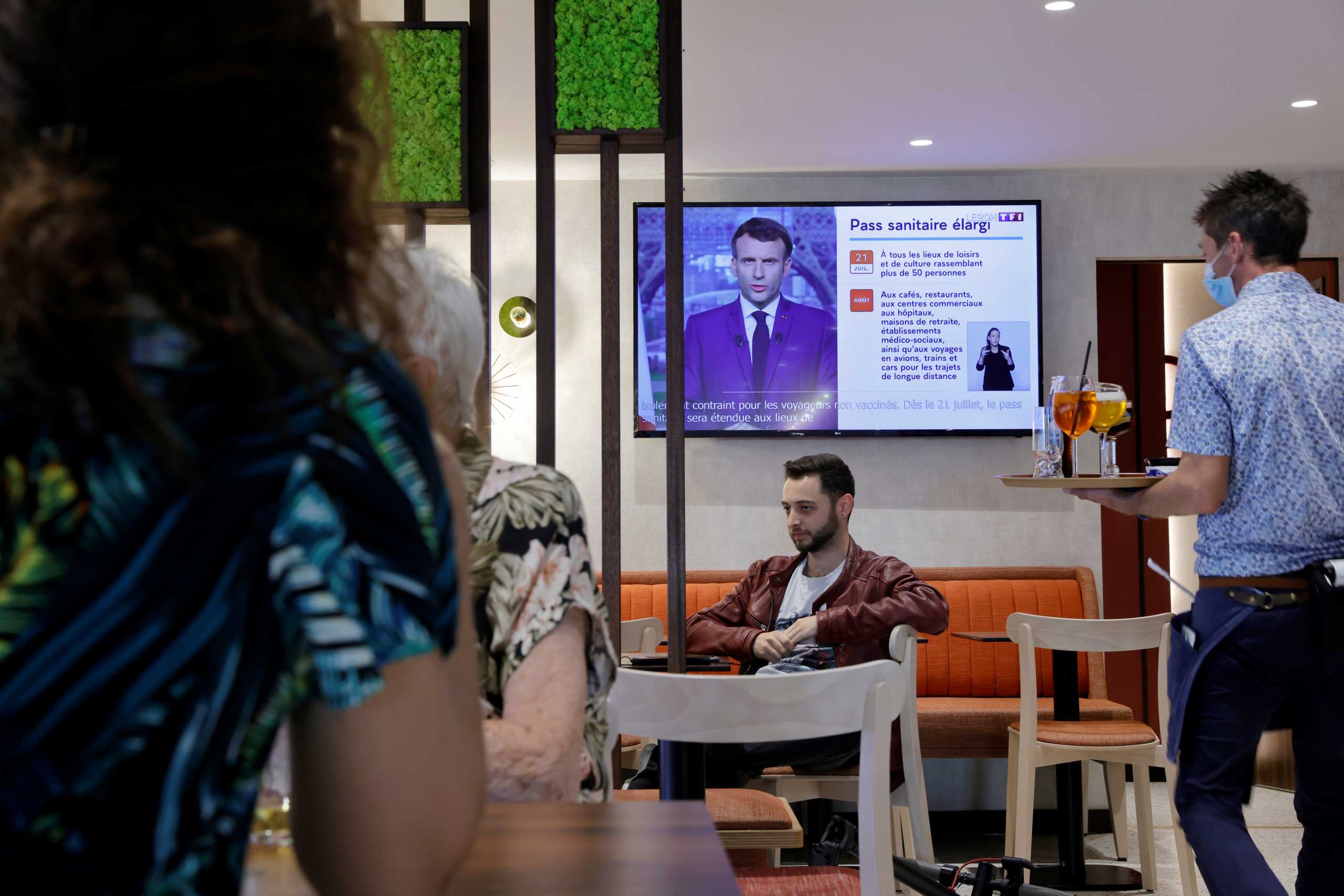 A waiter serves drinks in a pub as French President Macron, on TV, addresses the nation about the state of the coronavirus disease (COVID-19) outbreak, in Cambrai, France July 12, 2021. REUTERS