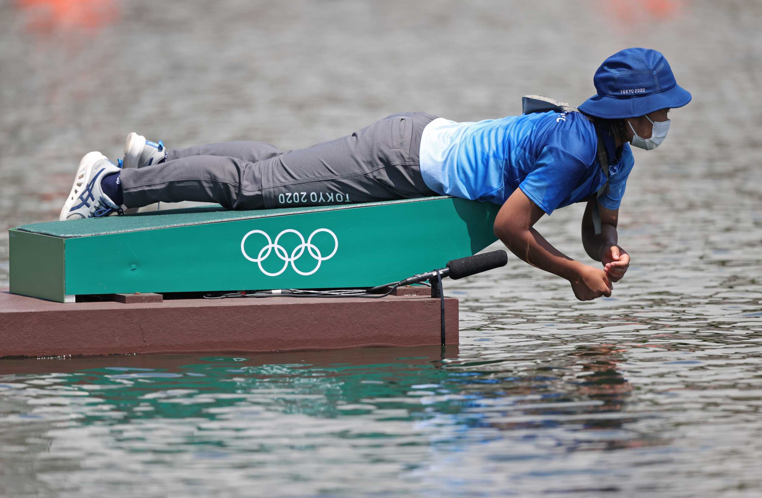 Tokyo 2020 Olympics - Rowing - Men's Lightweight Double Sculls - Heats - Sea Forest Waterway, Tokyo, Japan - July 24, 2021. A volunteer is seen wearing a protective face mask at the start of the heat REUTERS
