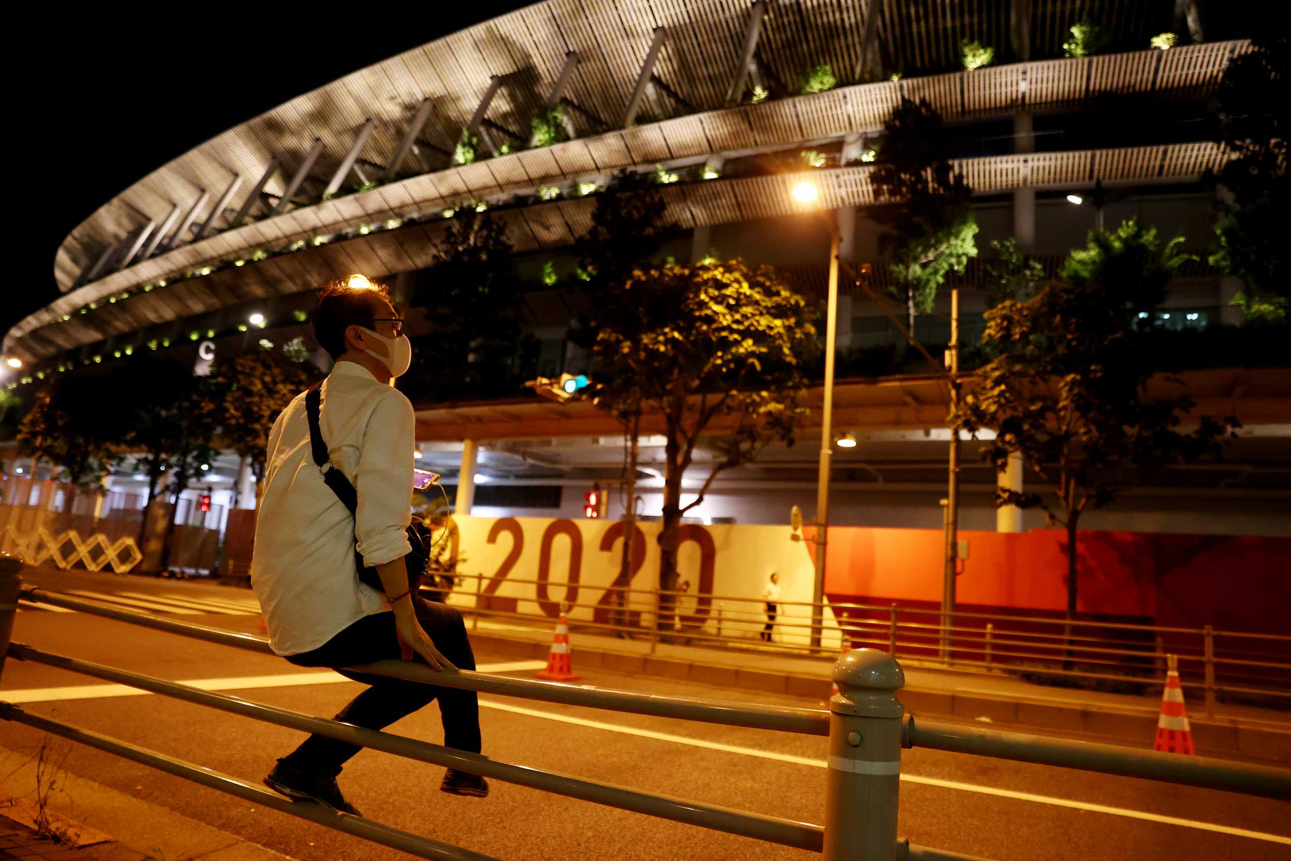 Tokyo 2020 Olympics - Olympic Stadium, Tokyo, Japan - July 22, 2021 A man wearing a mask sits outside the Olympic Stadium REUTERS