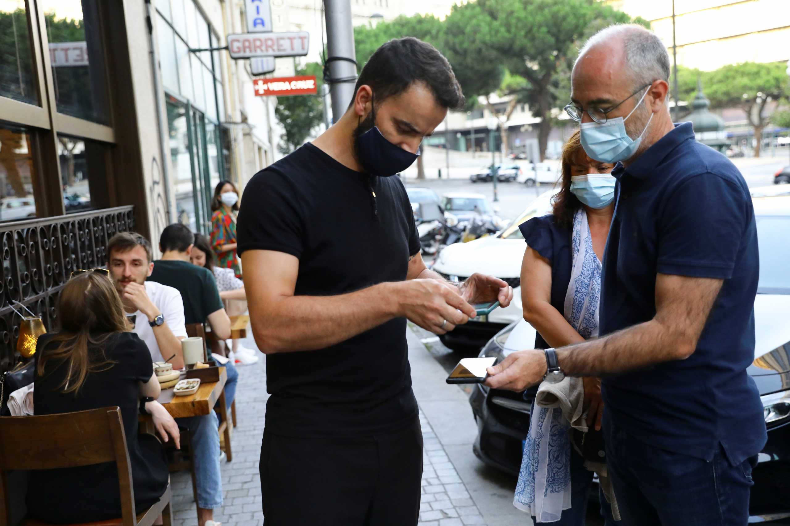 Restaurant staff checks a digital vaccination certificate at the entrance, on the day that Portugal's government imposed stricter rules in an attempt to bring under control a surge of coronavirus disease (COVID-19) cases, in Porto, Portugal, July 10, 2021. REUTERS