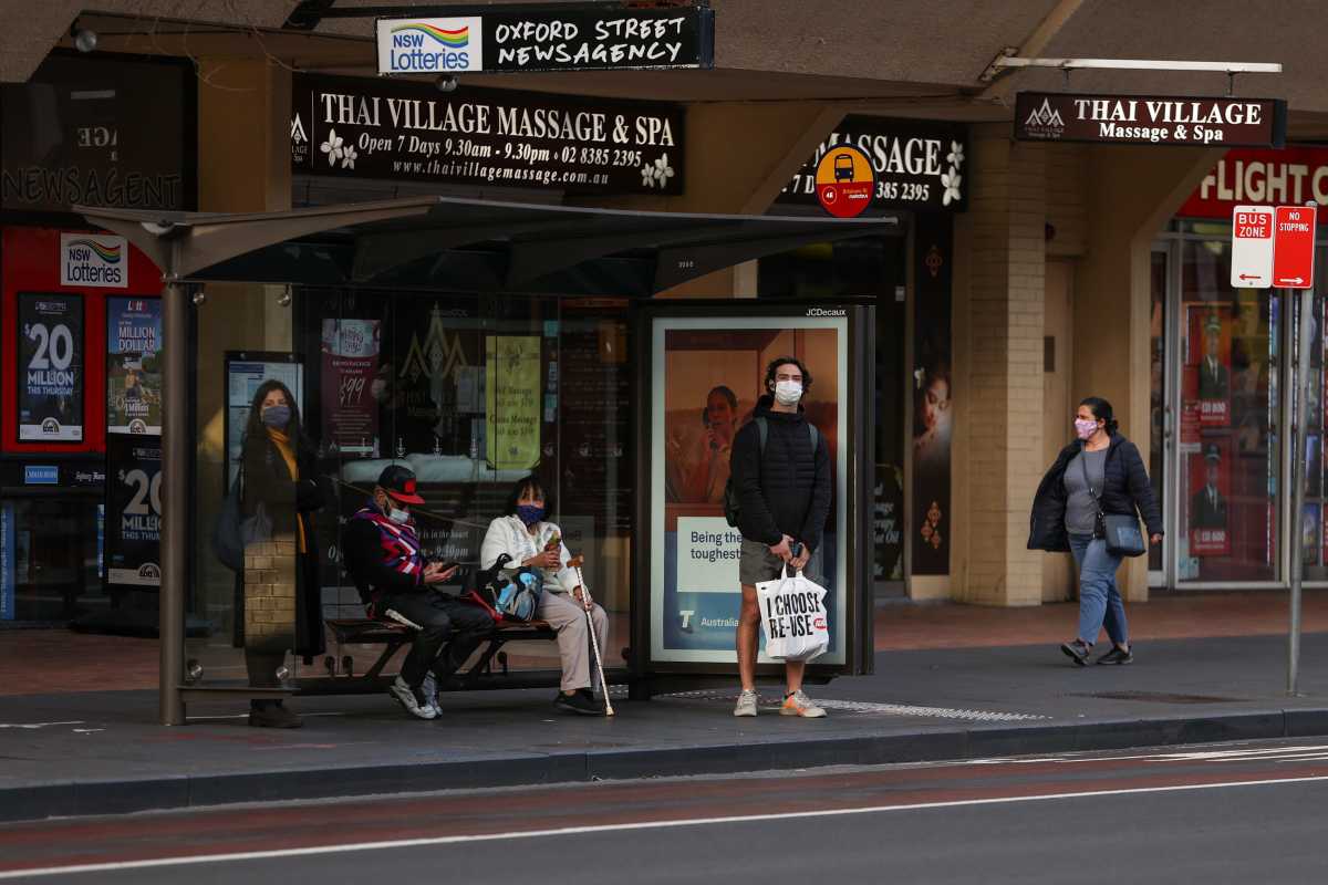 People wearing protective face masks wait at a bus stop during a lockdown to curb the spread of a coronavirus disease (COVID-19) outbreak in Sydney, Australia, July 22, 2021.  REUTERS