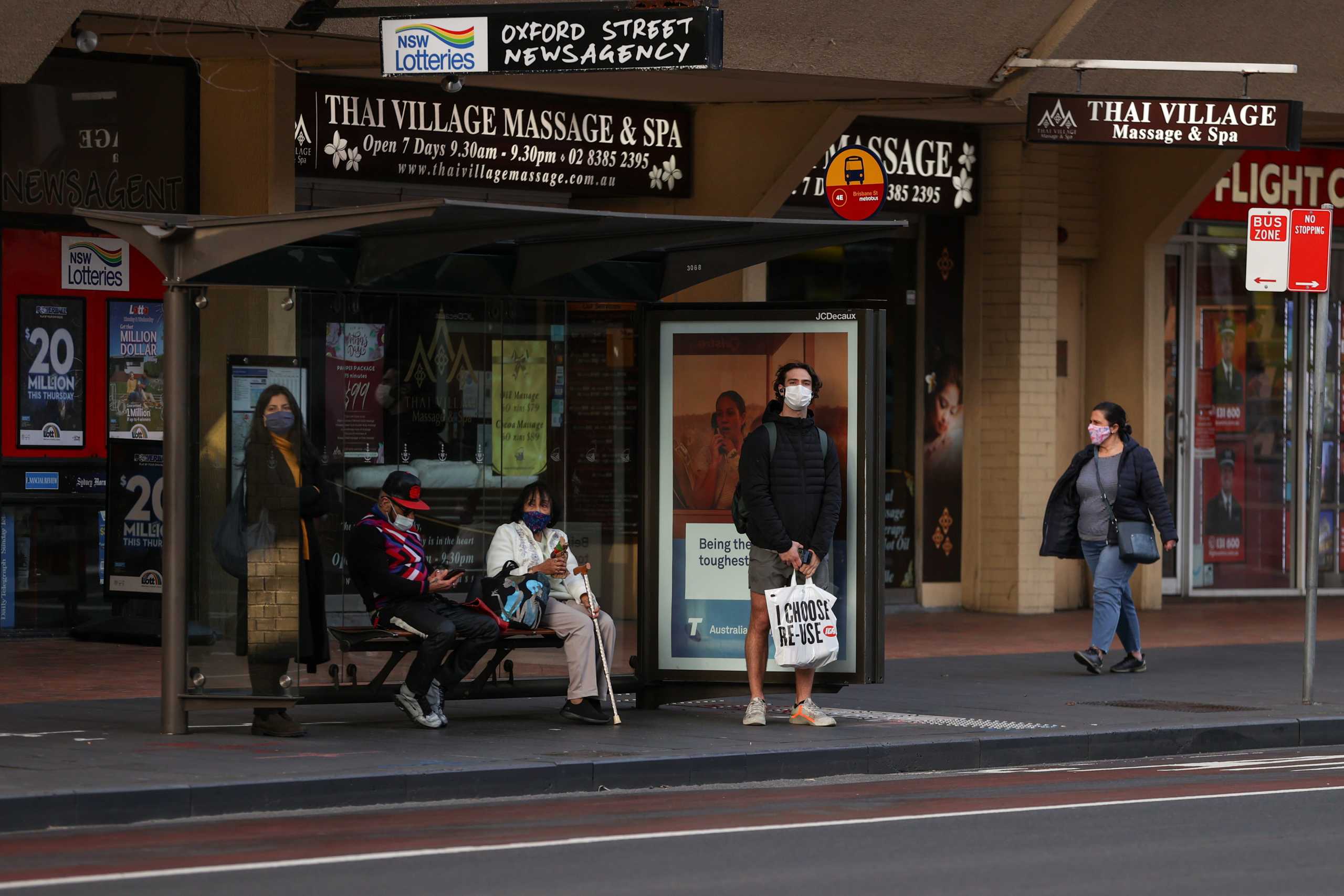 People wearing protective face masks wait at a bus stop during a lockdown to curb the spread of a coronavirus disease (COVID-19) outbreak in Sydney, Australia, July 22, 2021.  REUTERS