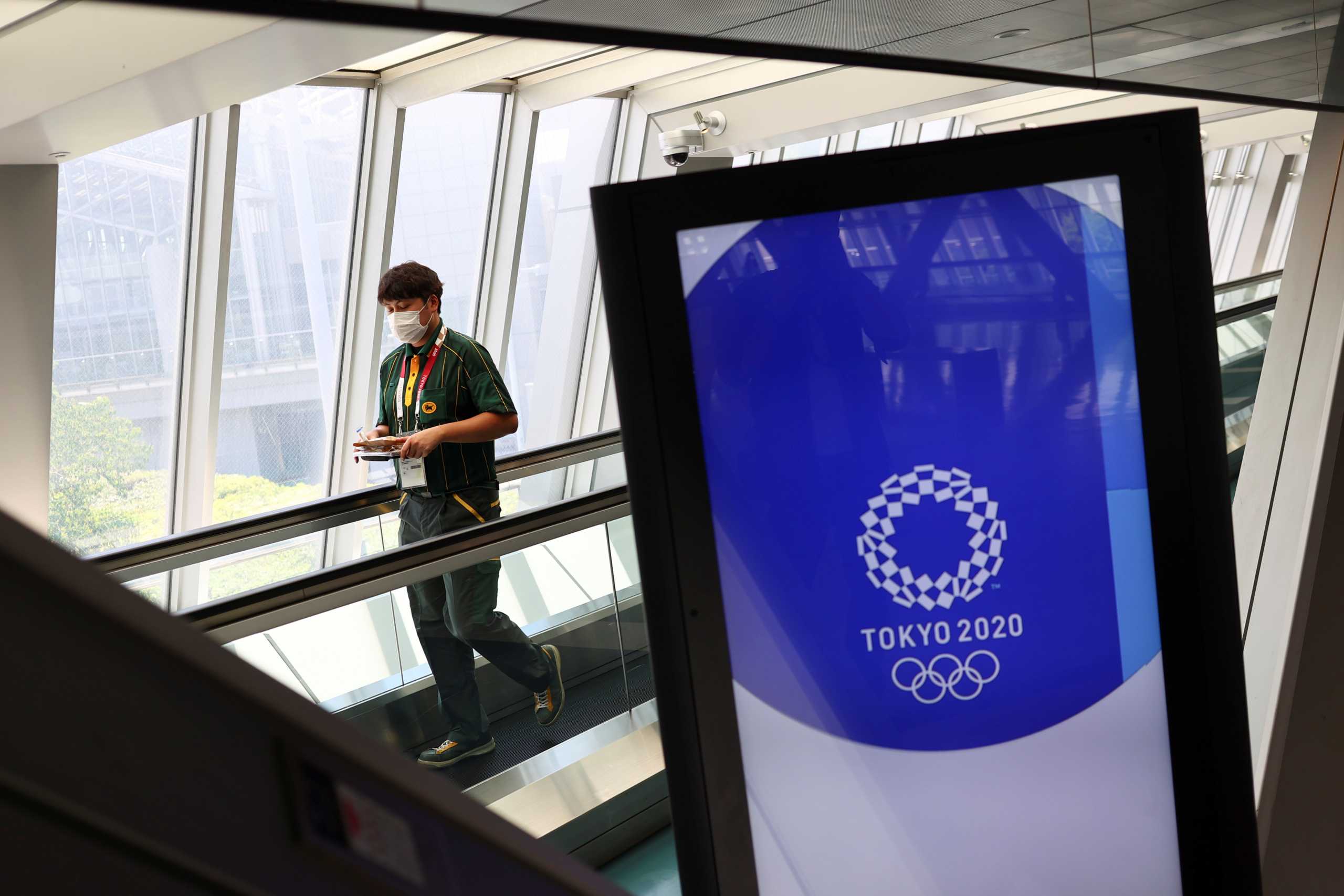 A man wearing a face mask walks past Tokyo 2020 Olympic Games signage at the Main Press Center during the coronavirus disease (COVID-19) outbreak in Tokyo, Japan, July 16, 2021.  REUTERS