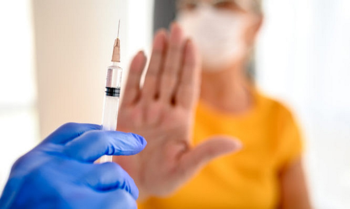 Close up of unrecognizable doctor trying to vaccinate its patient while she is refusing it.