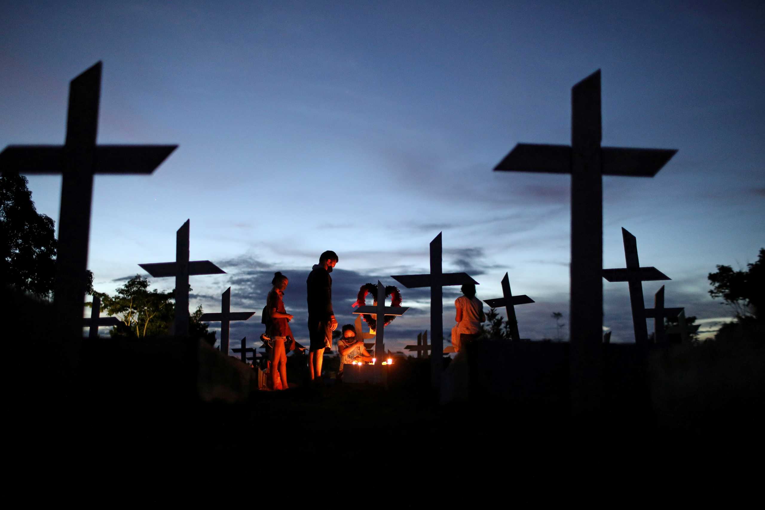 FILE PHOTO: Siblings, Amauri Ramos and Edmara Ramos are seen with their relatives as they visit the grave of their father, Edson Fonseca Ramos, who passed away due to the coronavirus disease (COVID-19),  at the Parque Taruma cemetery in Manaus, Brazil May 8, 2021. REUTERS