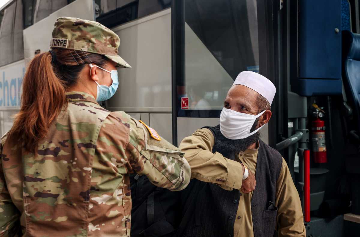 An Afghan refugee elbow bumps a U.S. Army officer before boarding a bus that will take refugees to a processing center, upon arrival at Dulles International Airport in Dulles, Virginia, U.S., August 31, 2021. REUTERS