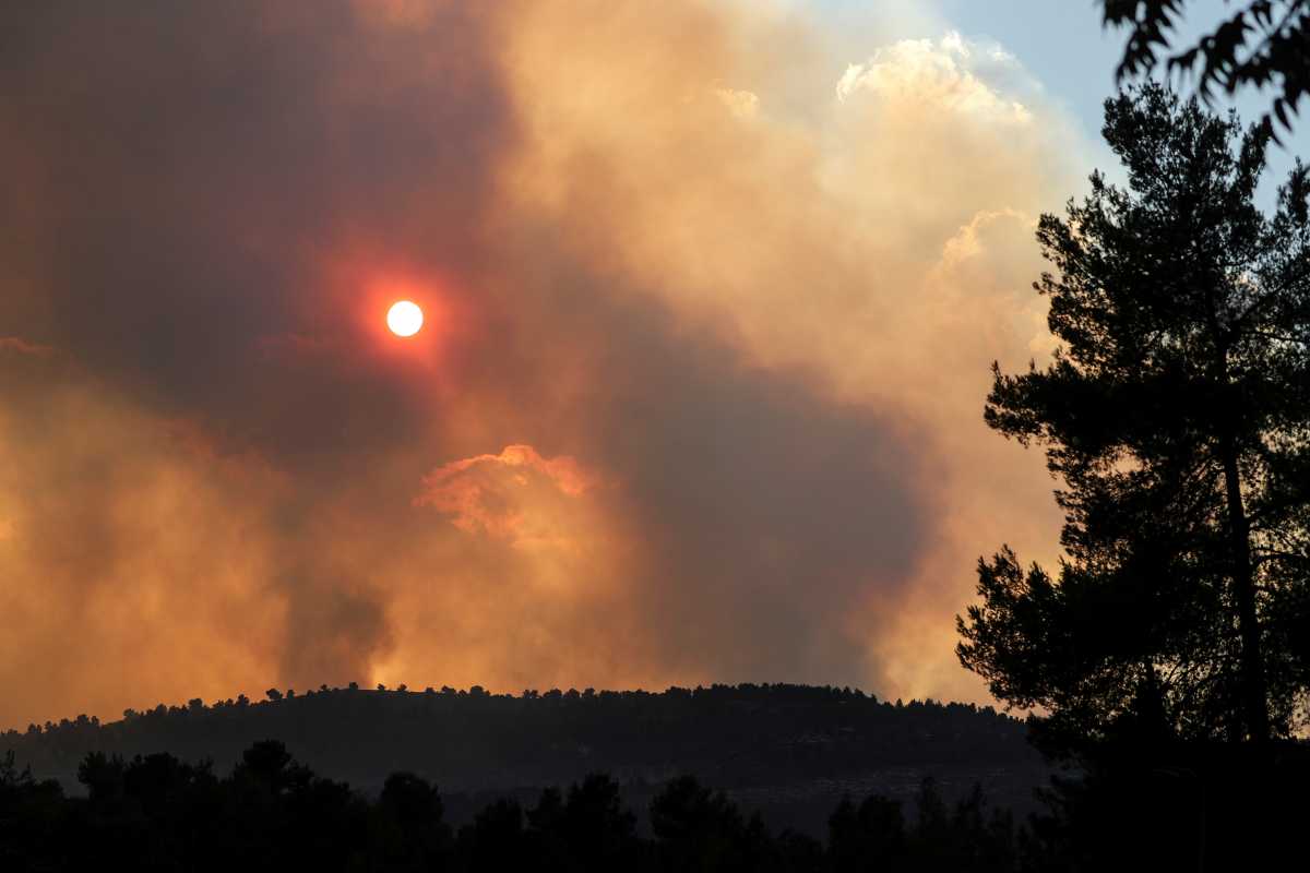The sun can be seen behind smoke over the mountains, caused by wildfire as firefighting planes and firefighters try to gain control over it in Givat Yearim, on the outskirts of Jerusalem August 15, 2021. REUTERS