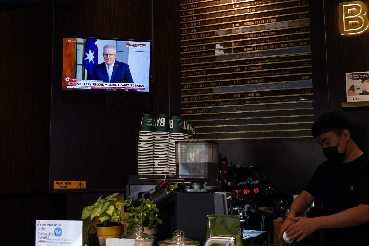 Australian Prime Minister Scott Morrison, speaking about a military rescue mission in Kabul, Afghanistan, is seen on a cafe television as a barista prepares coffees for takeaway service during a lockdown to curb the spread of a coronavirus disease (COVID-19) outbreak in Sydney, Australia, August 18, 2021.  REUTERS