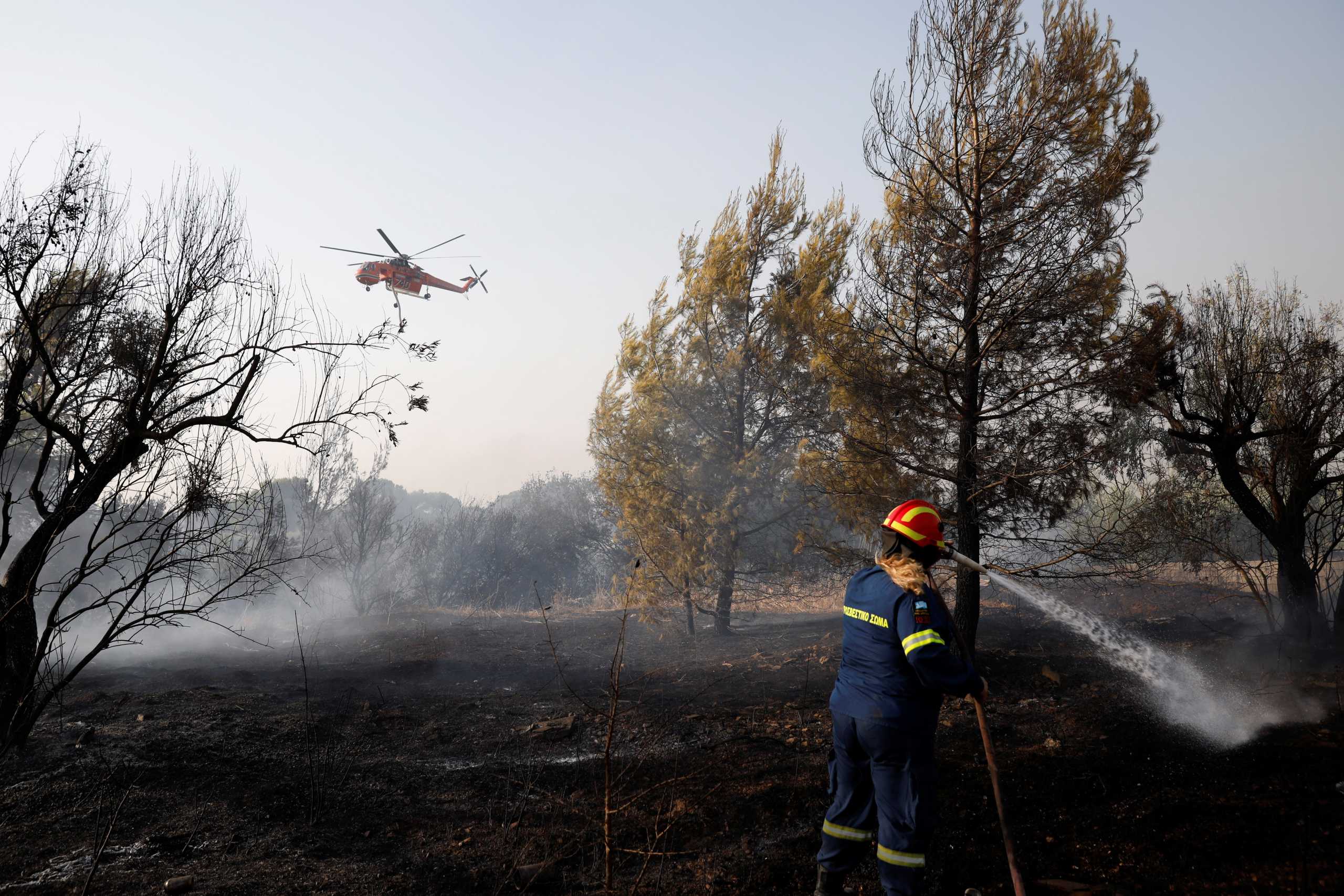 A firefighter sprays water in an attempt to help fight a wildfire at Varympompi suburb north of Athens, Greece, August 4, 2021. REUTERS