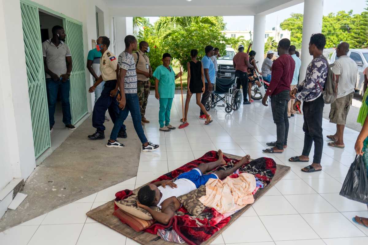 A man injured during last Saturday 7.2 magnitude quake lays on a plywood at the entrance of the OFATMA hospital in Les Cayes, Haiti August 20, 2021. REUTERS