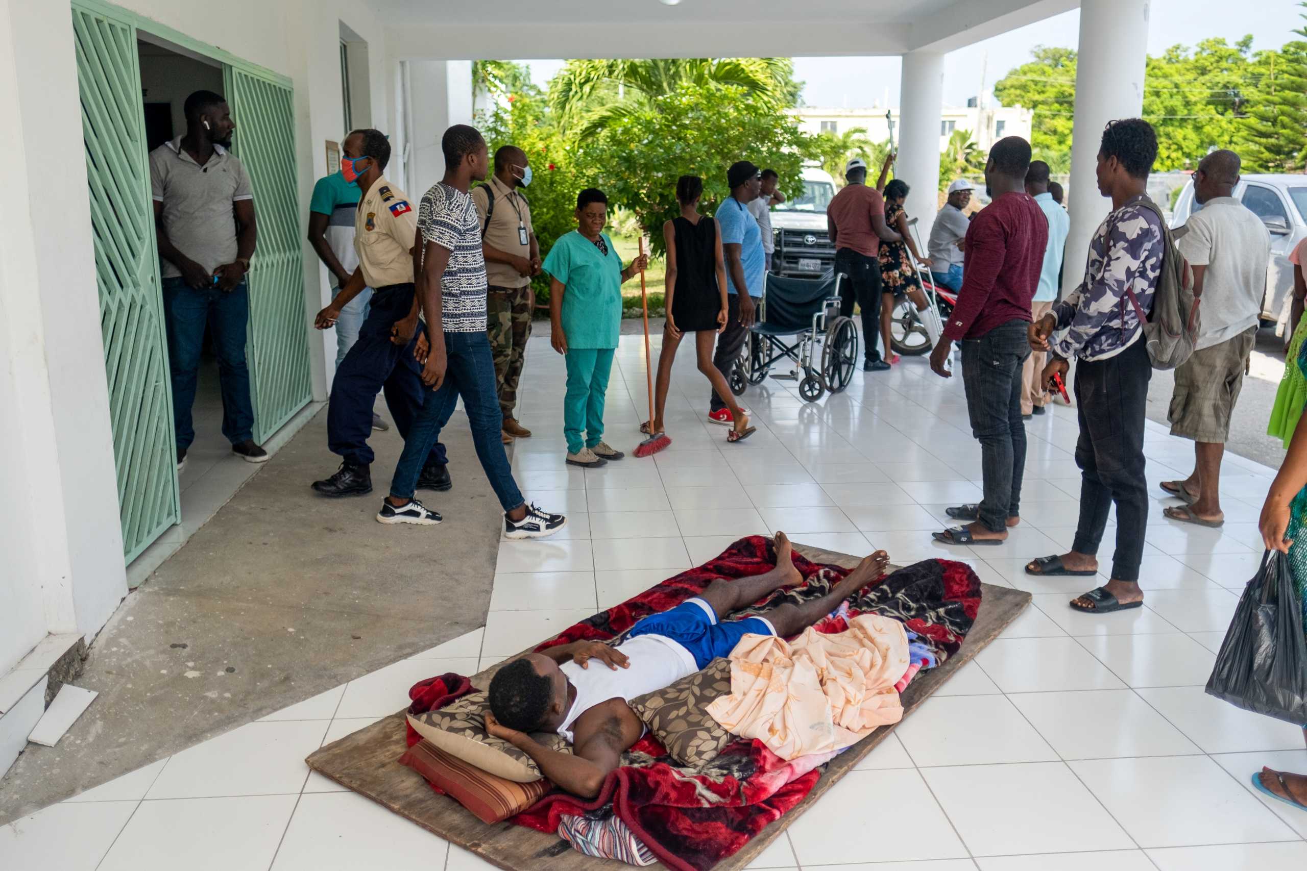 A man injured during last Saturday 7.2 magnitude quake lays on a plywood at the entrance of the OFATMA hospital in Les Cayes, Haiti August 20, 2021. REUTERS