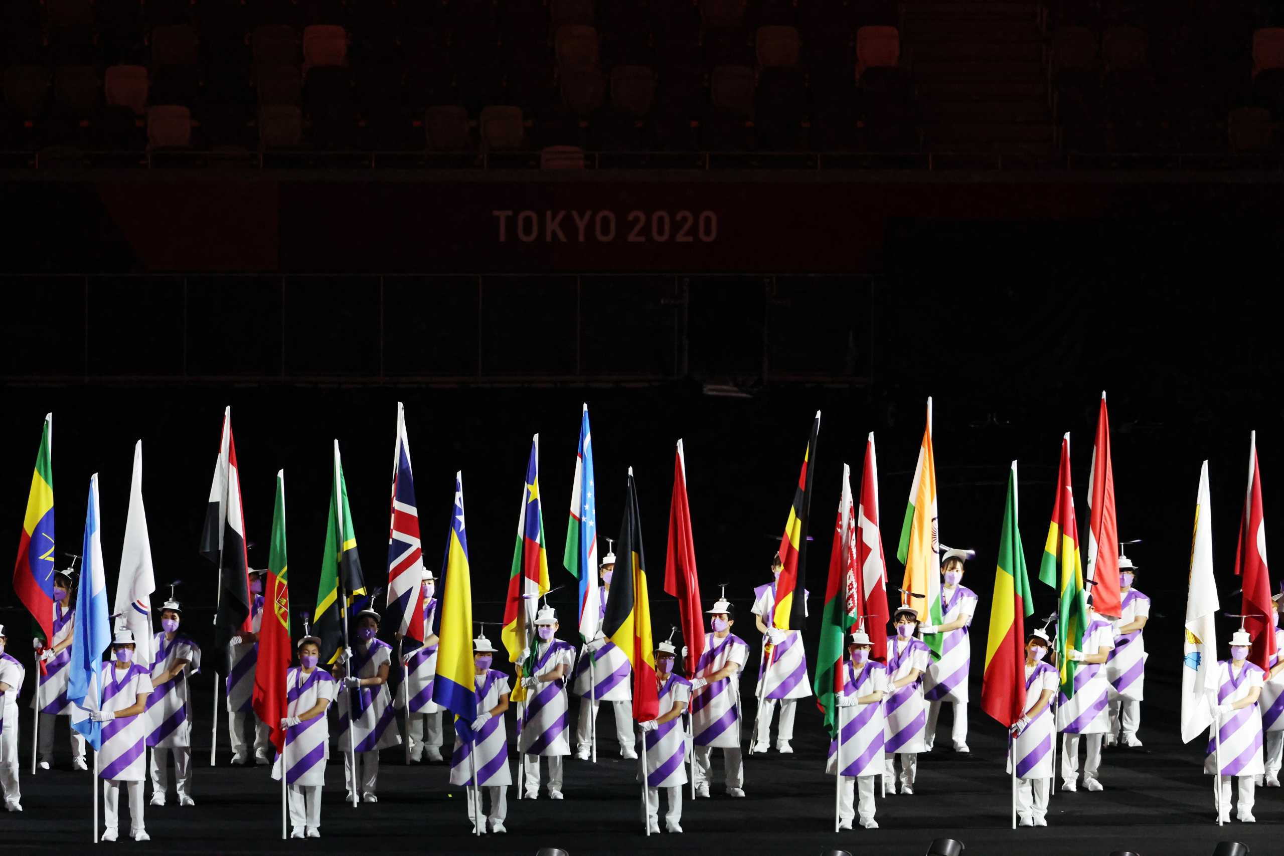 Tokyo 2020 Paralympic Games - The Tokyo 2020 Paralympic Games Opening Ceremony - Olympic Stadium, Tokyo, Japan - August 24, 2021.  Volunteers hold national flags during the athletes parade at the opening ceremony. REUTERS