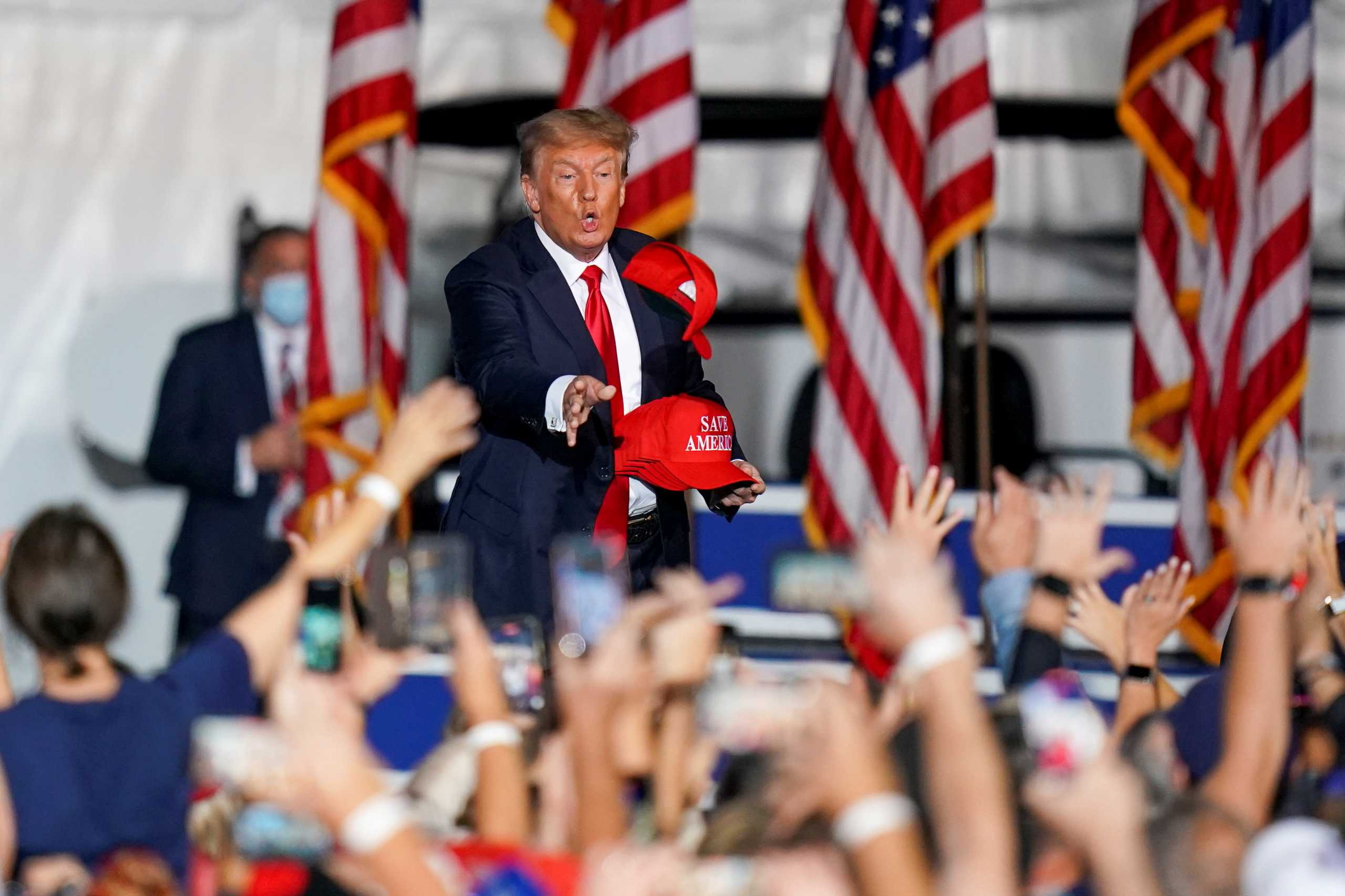 Former U.S. President Donald Trump tosses a hat prior to him speaking during a rally in Cullman, Alabama, U.S., August 21, 2021.  REUTERS