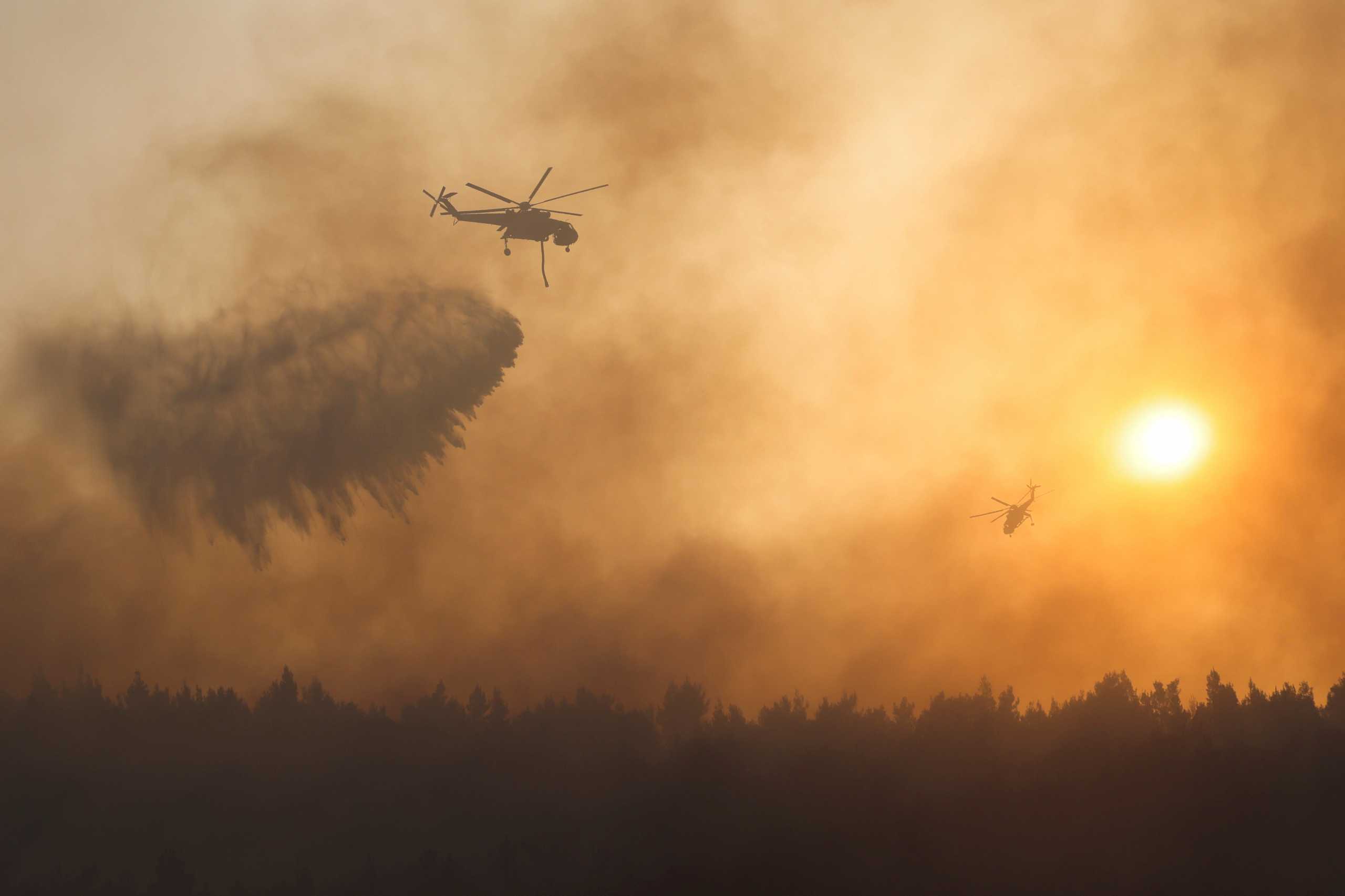 A firefighting helicopter makes a water drop as a wildfire continues to rage at Varympompi suburb north of Athens, Greece, August 4, 2021. REUTERS
