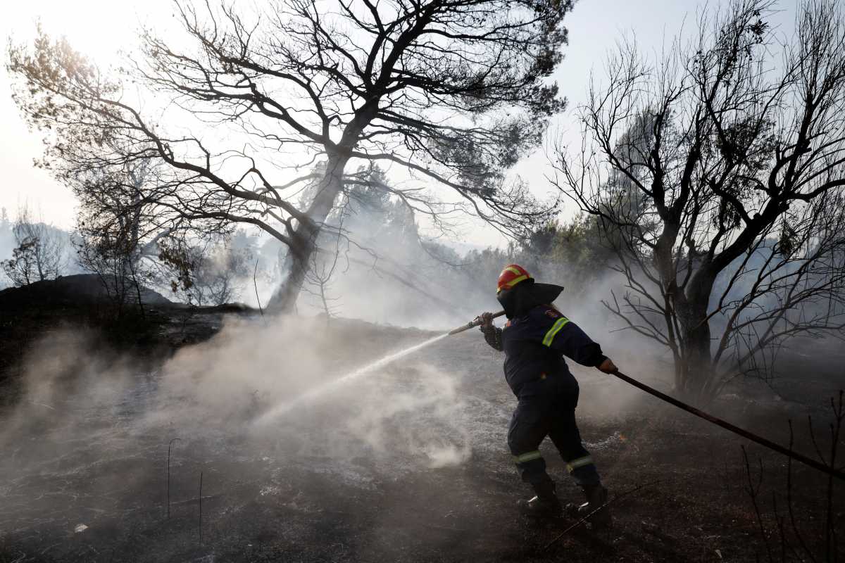 A firefighter sprays water in an attempt to help fight a wildfire at Varympompi suburb north of Athens, Greece, August 4, 2021. REUTERS