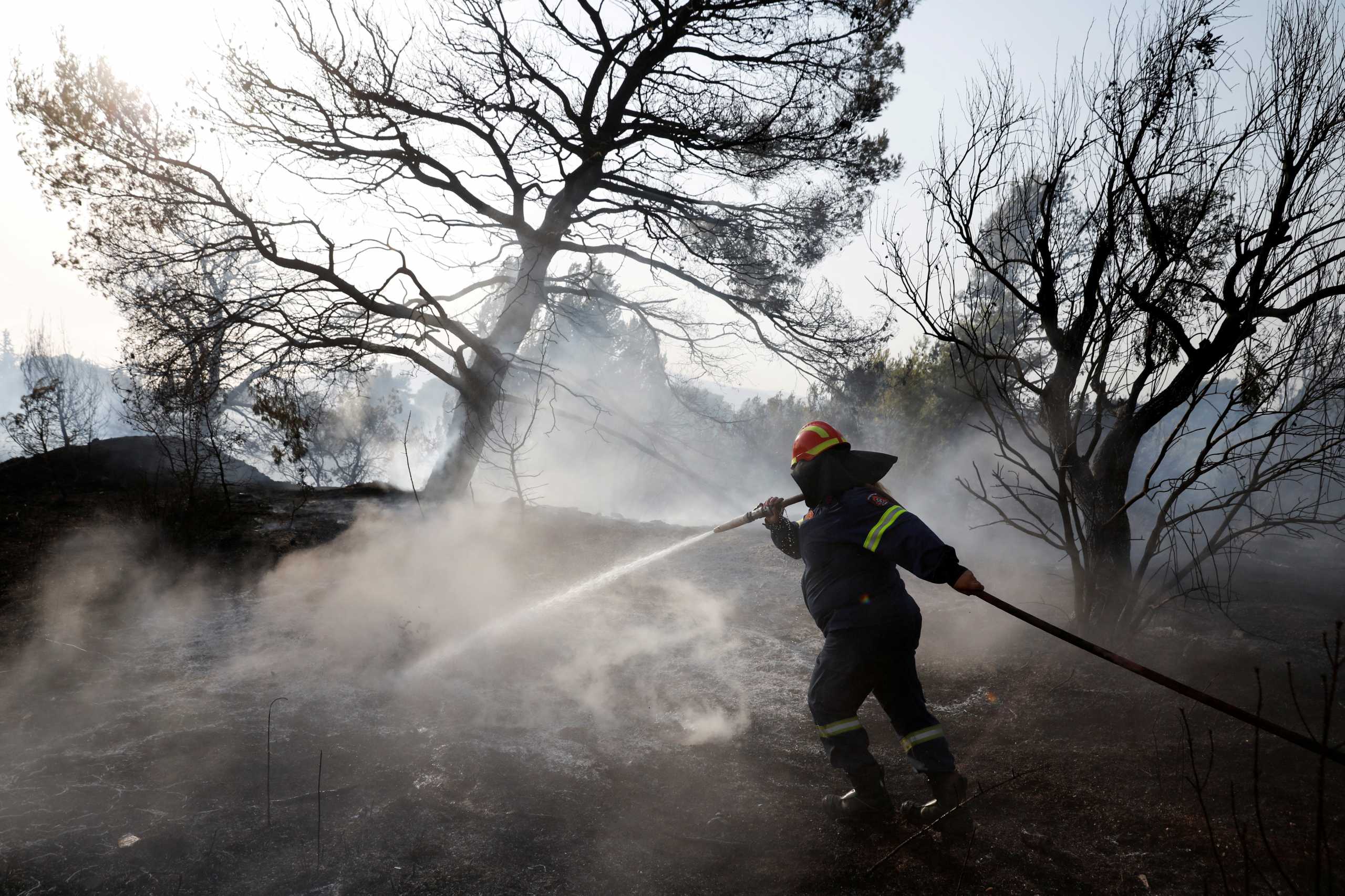 A firefighter sprays water in an attempt to help fight a wildfire at Varympompi suburb north of Athens, Greece, August 4, 2021. REUTERS