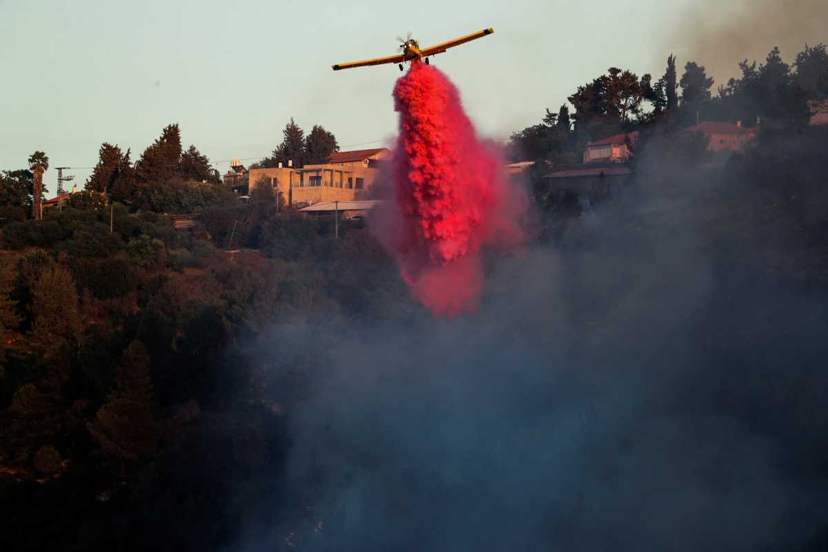 A firefighting plane disperses fire retardant as it assists in extinguishing a fire near the Israeli village of Beit Meir on the outskirts of Jerusalem August 16, 2021. REUTERS