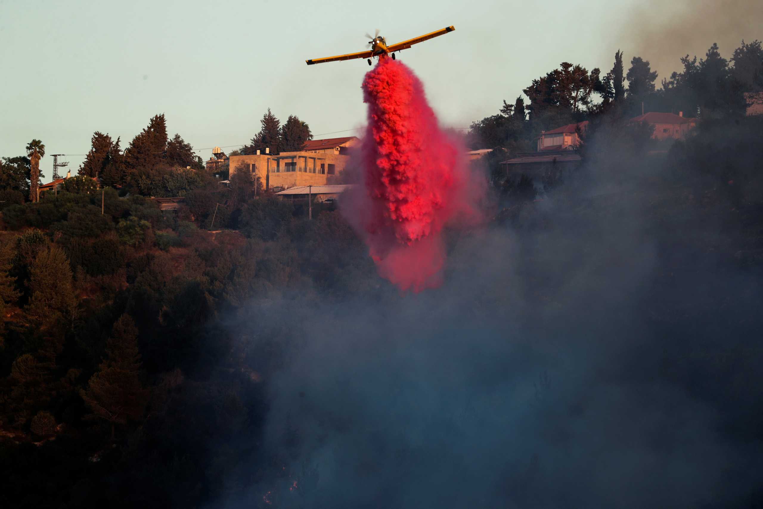 A firefighting plane disperses fire retardant as it assists in extinguishing a fire near the Israeli village of Beit Meir on the outskirts of Jerusalem August 16, 2021. REUTERS