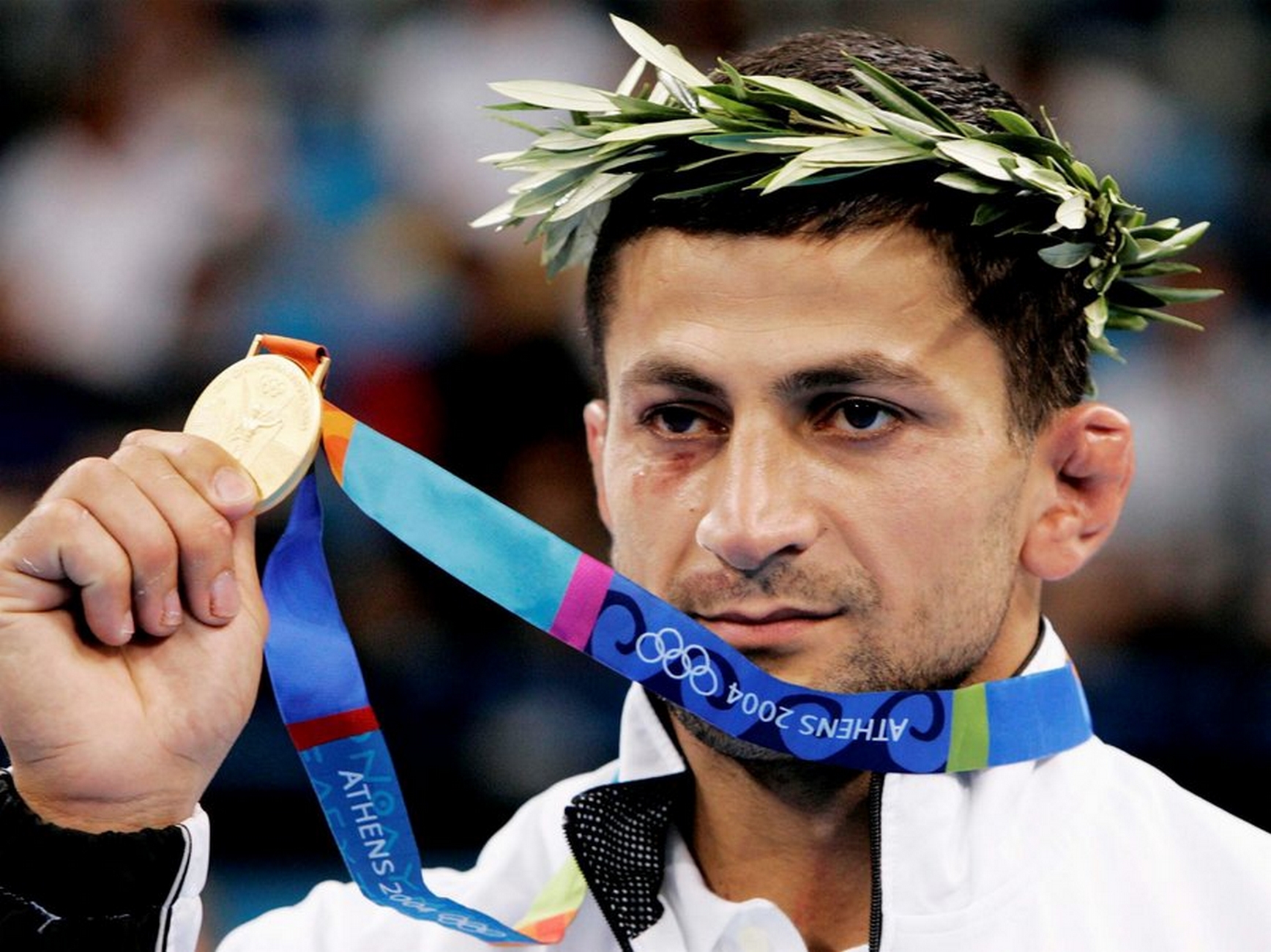 epa000254547 Zurab Zviadauri of Georgia shows his gold medal after the victory ceremony for  the men's 90kg Judo competition of the Athens 2004 Olympic Games at the Ano Liosia Indoor Arena, Wednesday 18 August 2004.    epa