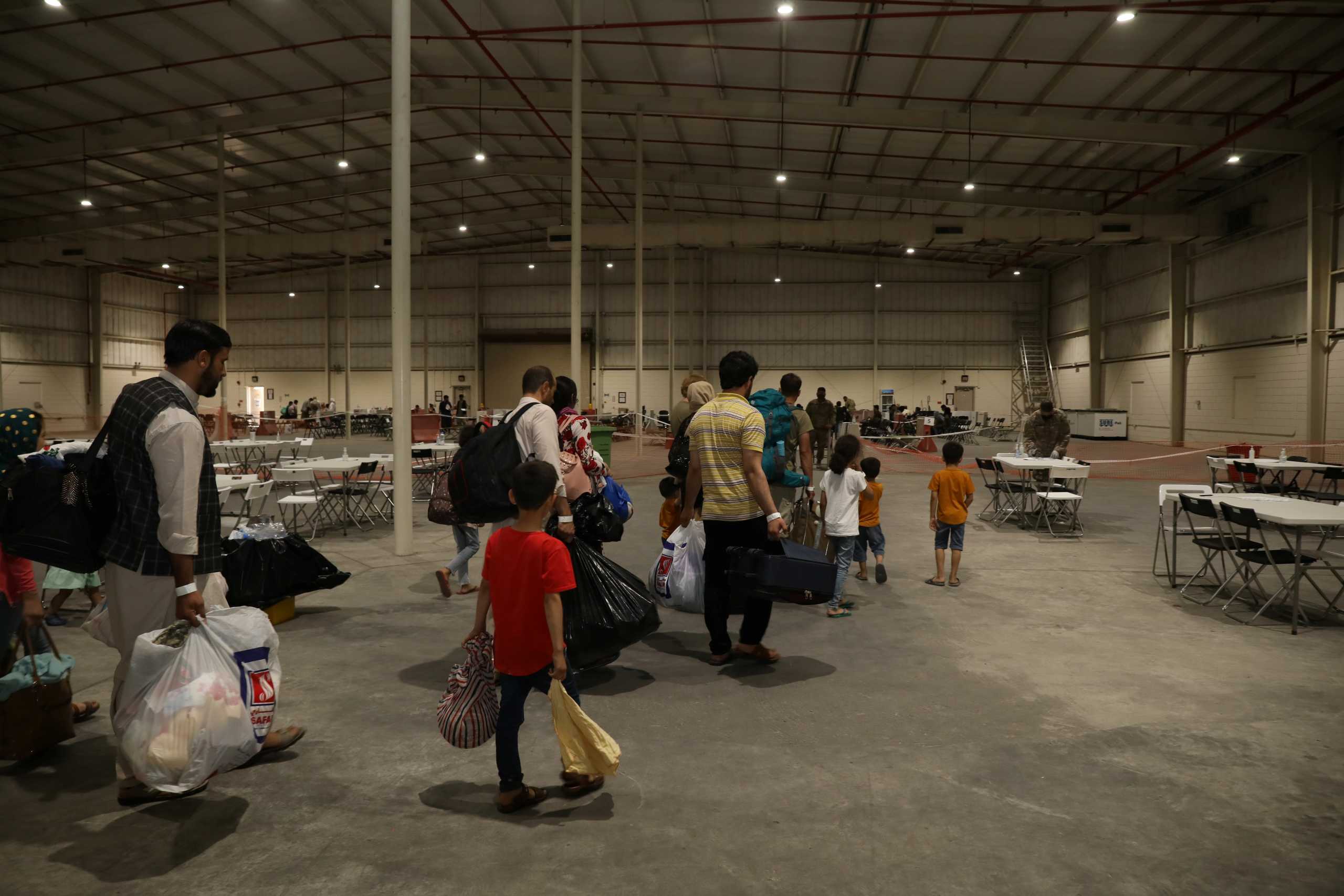 Special Immigrants from Afghanistan walk through the in-processing building after their evacuation at Camp As Sayliyah, Qatar, August 20, 2021. Picture taken August 20, 2021.  U.S. Army