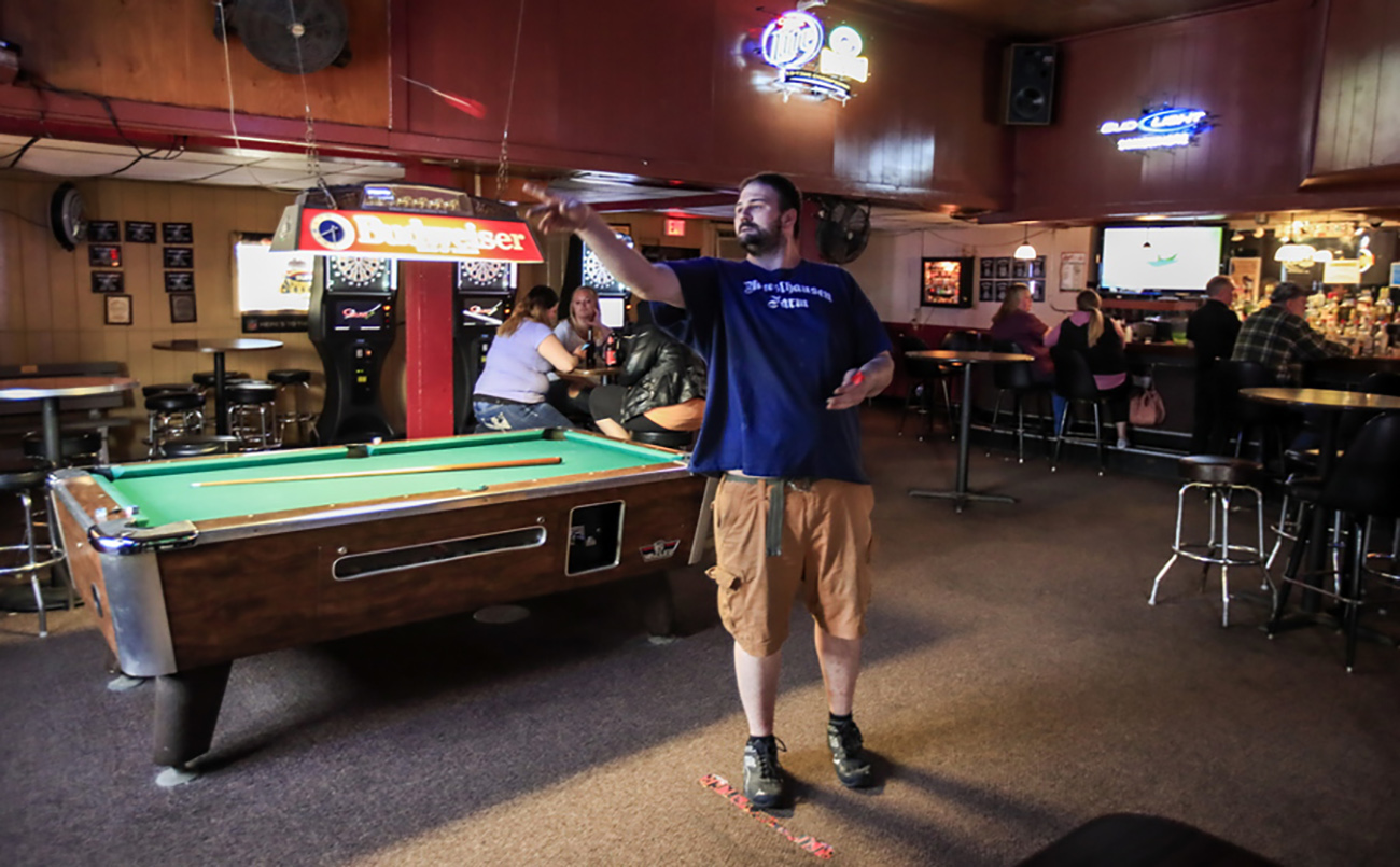 epa08423184 A man plays darts while other people sit and drink at the Somewhere bar in Fond du Lac, Wisconsin, USA, 14 May 2020. The Wisconsin Supreme Court reportedly ended Governor Tony Evers stay at home order in a four to three ruling on 13 May. A number of local bars immediately opened and patrons took advantage of the ruling to visit prompting local officials to issue their own orders in an effort to combat the coronavirus SARS-CoV-2 which causes the Covid-19 disease.  EPA