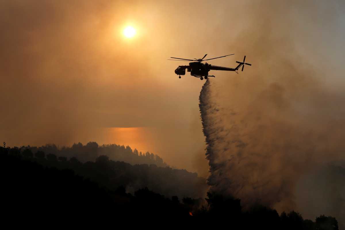 A firefighting helicopter makes a water drop as a wildfire burns near the village of Ziria, near Patras, Greece, August 1, 2021. REUTERS
