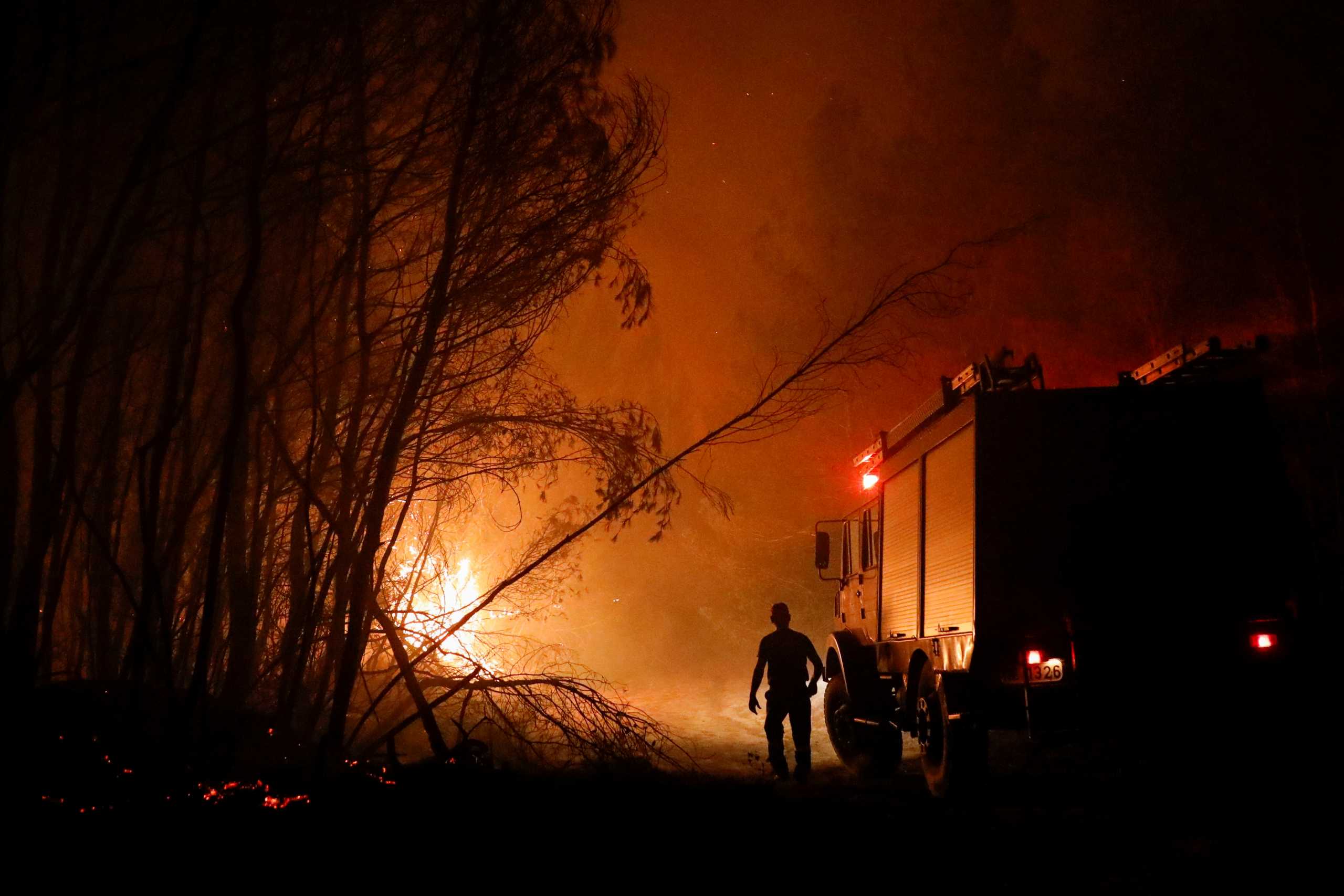 Flames rise next to firefighting vehicles as a wildfire burns near the village of Ziria, near Patras, Greece, August 1, 2021. REUTERS