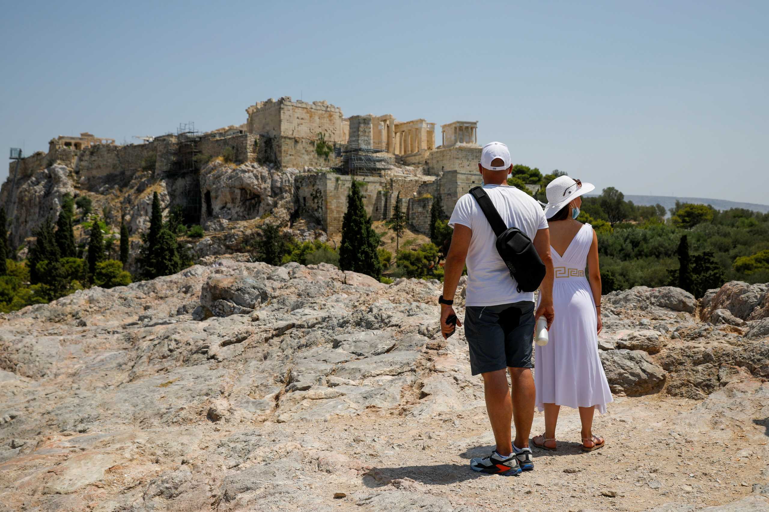 People visit the Areios Pagos hill with empty Acropolis in the background, closed to the public during a heatwave in Athens, Greece, July 30, 2021. REUTERS