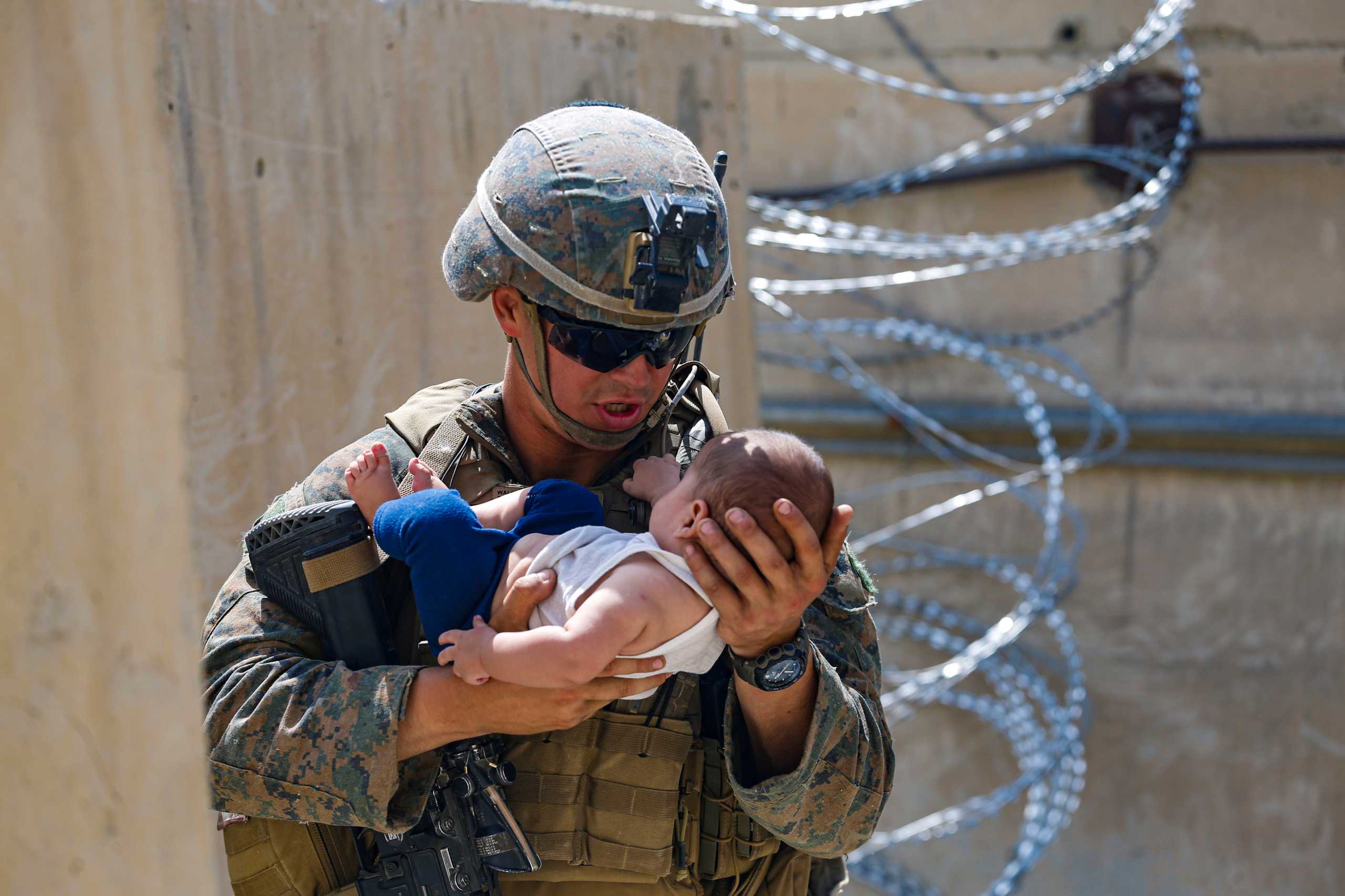 A U.S. Marine comforts an infant while they wait for the mother during an evacuation at Hamid Karzai International Airport, Afghanistan, August 21, 2021. Picture taken August 21, 2021.  U.S. Marine Corps