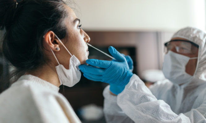 Doctor in protective workwear taking nose swab test from young woman