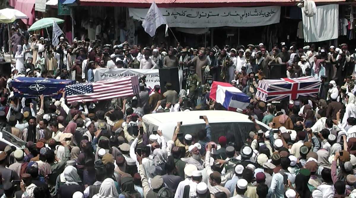 Crowd carries makeshift coffins draped in NATO's, U.S. and a Union Jack flags during a pretend funeral  on a street in Khost, Afghanistan August 31, 2021, in this screen grab obtained from a social media video. ZHMAN TV