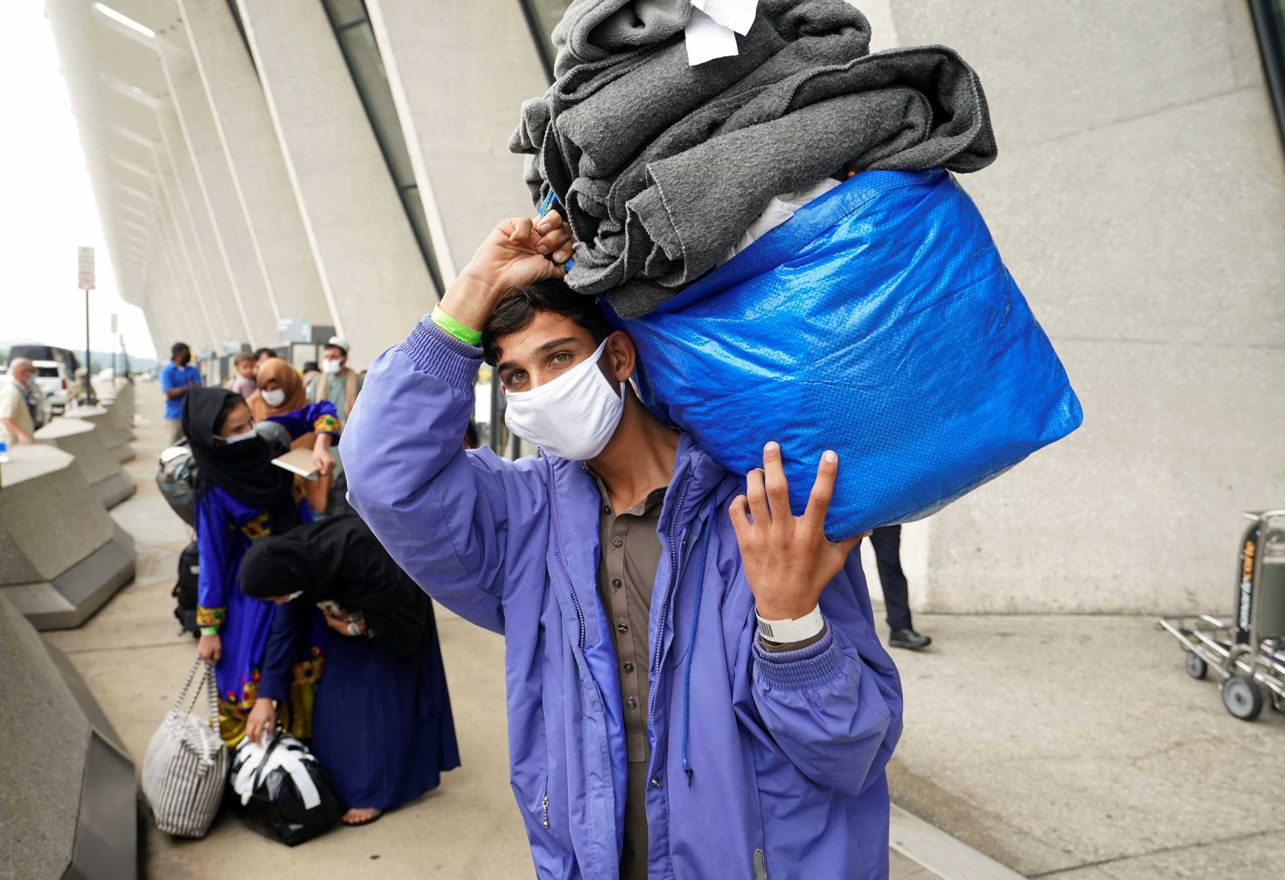 A day after U.S. forces completed their troop withdrawal from Afghanistan, an Afghan man carries his possessions onto a bus taking refugees to a processing center upon their arrival at Dulles International Airport in Dulles, Virginia, U.S.,  September 1, 2021. REUTERS