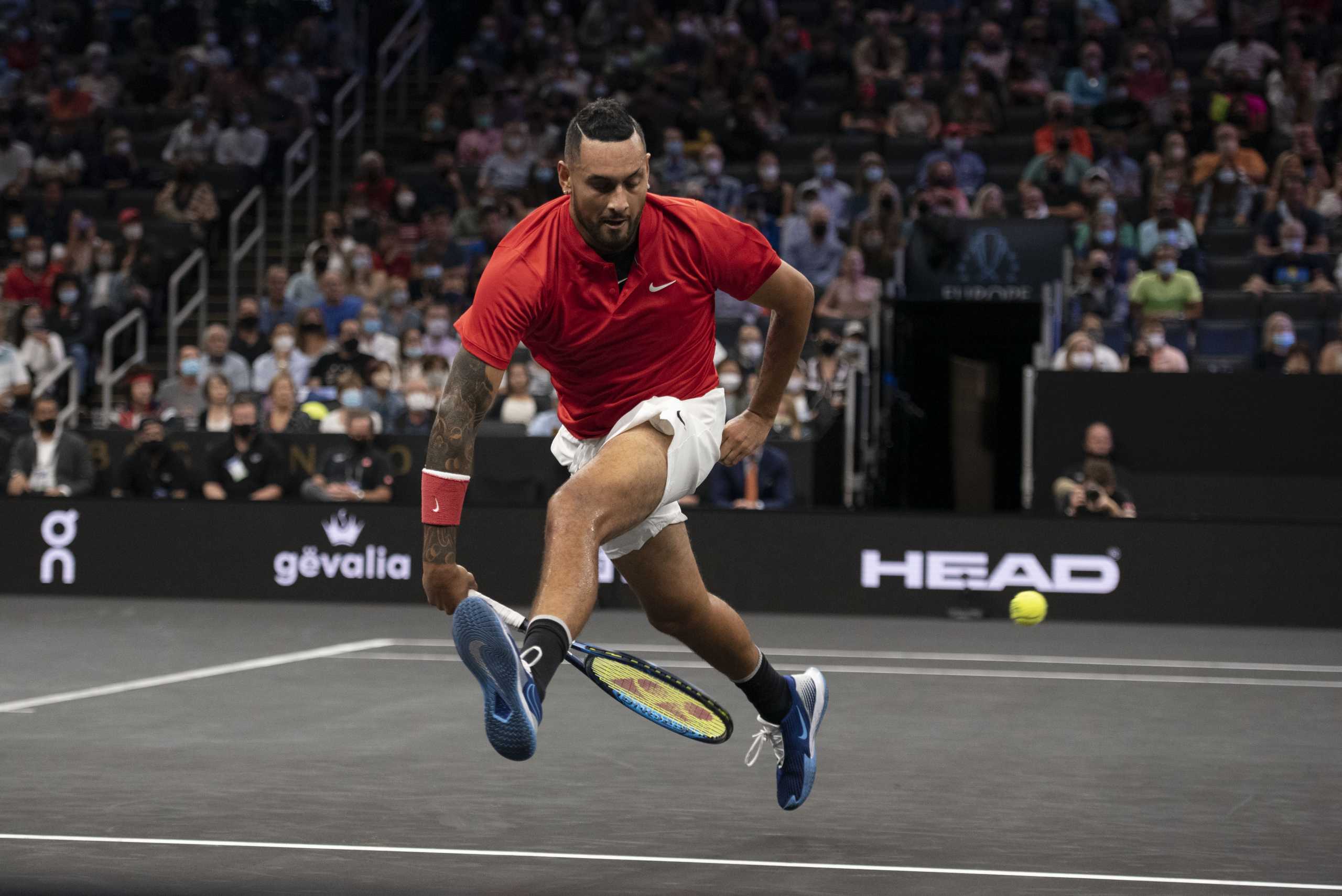 Sep 25, 2021; Boston, MA, USA;  Team World player Nick Kyrgios attempts a shot between his legs during the first set of his match against Team Europe player Stefanos Tsitsipas at TD Garden. Mandatory Credit: Richard Cashin-USA TODAY Sports