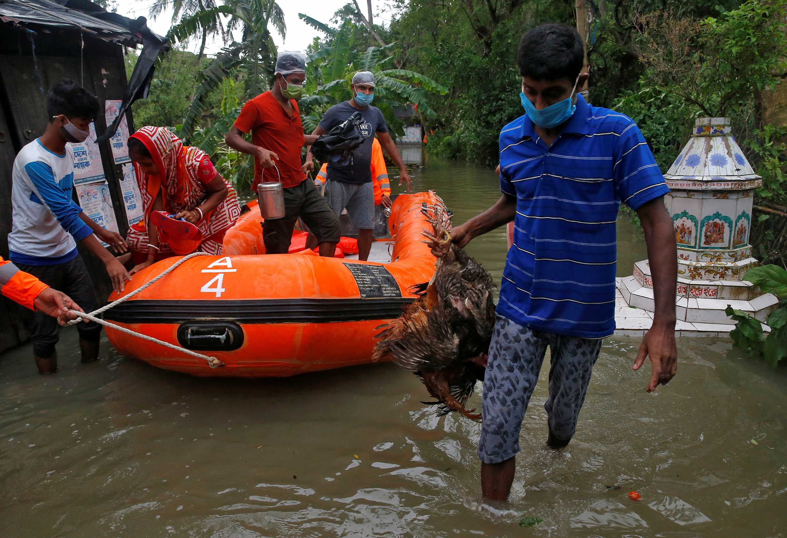 FILE PHOTO: People wearing masks to protect them from the coronavirus are evacuated from a flooded area by members of the National Disaster Response Force as Cyclone Yaas makes landfall at Ramnagar  in  West Bengal, India, May 26, 2021. REUTERS