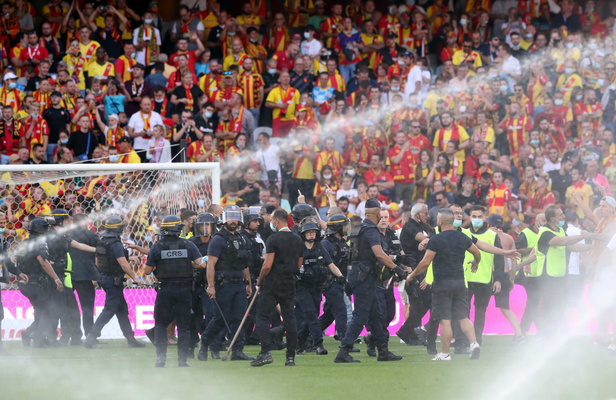 Soccer Football - Ligue 1 - RC Lens v Lille - Stade Bollaert-Delelis, Lens, France - September 18, 2021 RC Lens fans invade the pitch as police officers and stewards escort them off the pitch during the match REUTERS