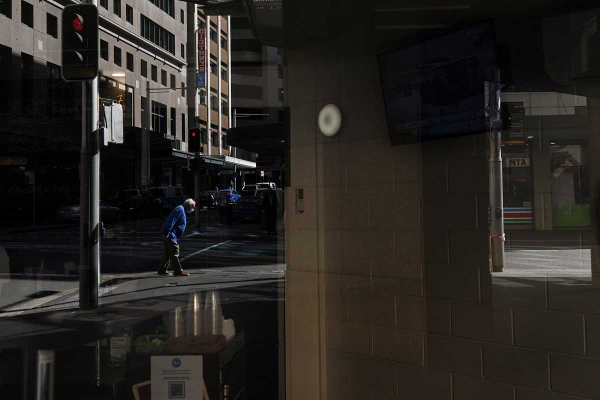 A pedestrian in a protective face mask, seen reflected in the window of a closed cafe, walks through the city centre during a lockdown to curb the spread of a coronavirus disease (COVID-19) outbreak in Sydney, Australia, September 24, 2021.  REUTERS