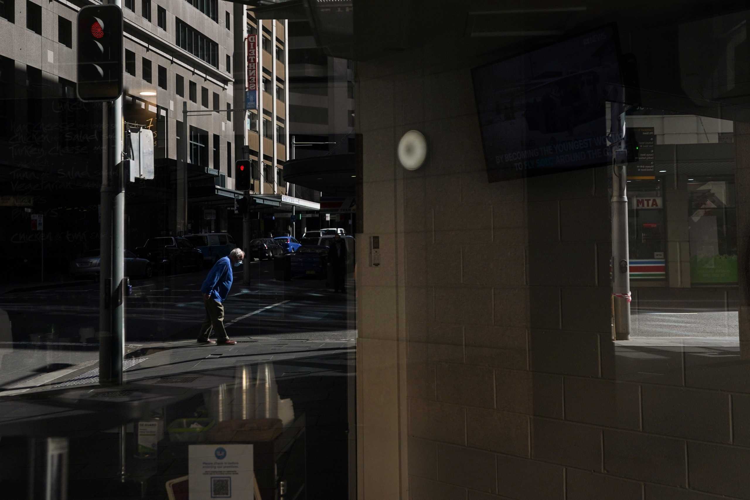 A pedestrian in a protective face mask, seen reflected in the window of a closed cafe, walks through the city centre during a lockdown to curb the spread of a coronavirus disease (COVID-19) outbreak in Sydney, Australia, September 24, 2021.  REUTERS