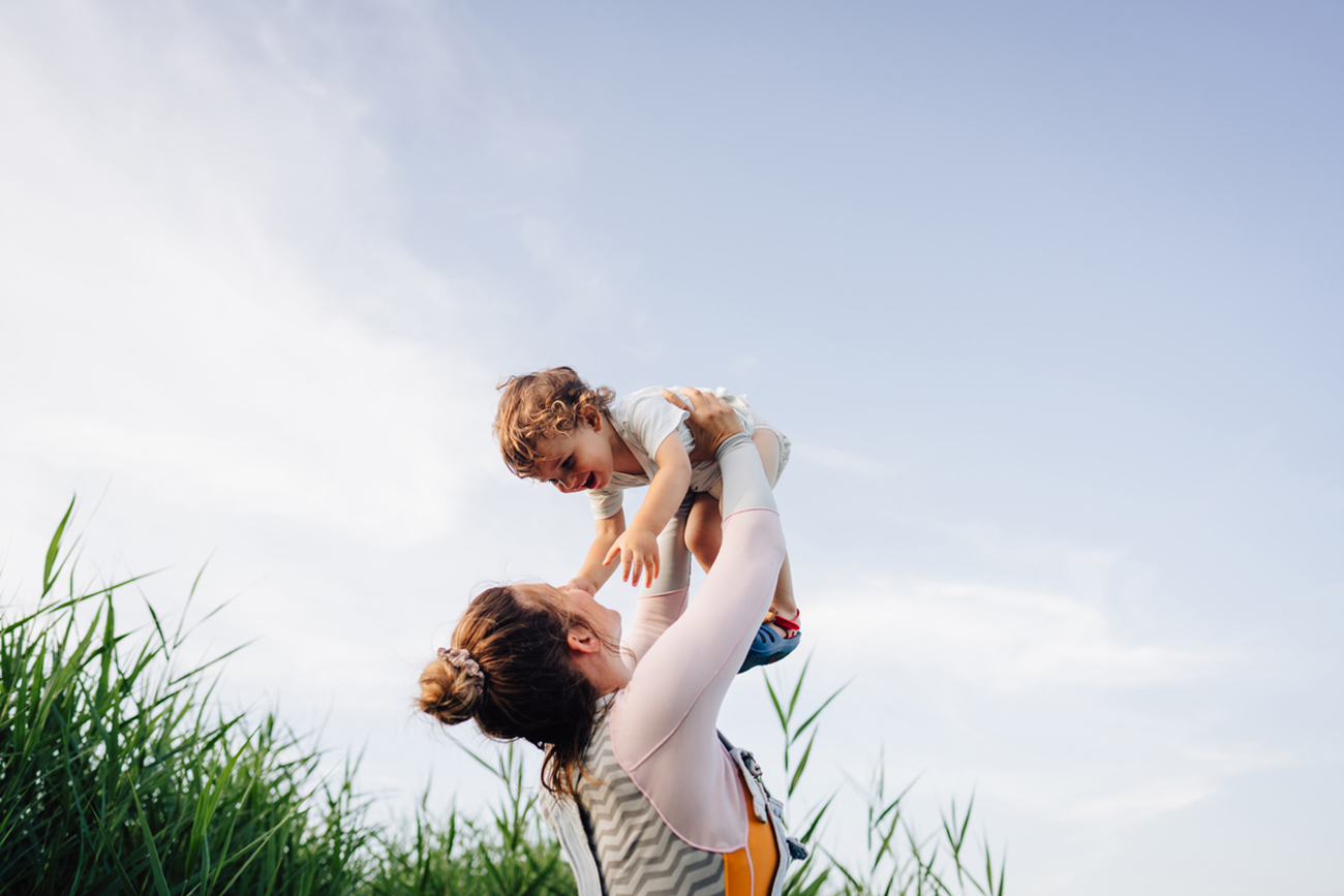 Photo of a young mother spending summer days by the lake with her little boy, who is still a toddler