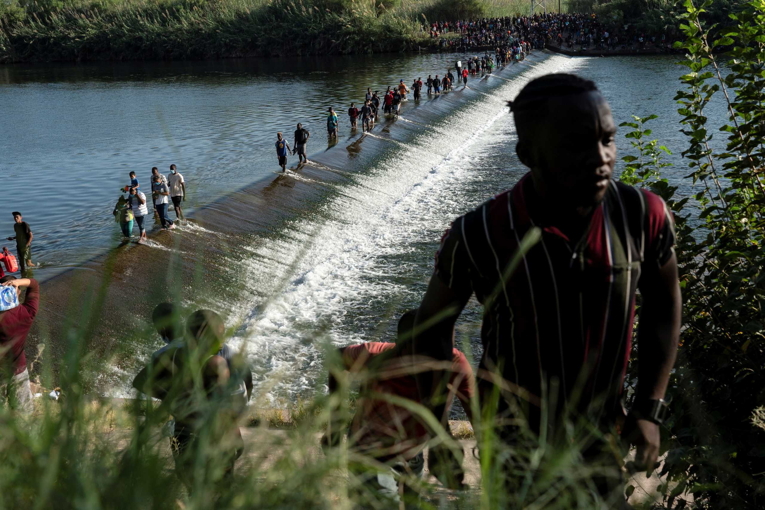 Migrants seeking asylum in the U.S. walk in the Rio Grande river near the International Bridge between Mexico and the U.S., as they wait to be processed, in Ciudad Acuna, Mexico, September 16, 2021. According to officials, some migrants cross back and forth into Mexico to buy food and supplies. REUTERS