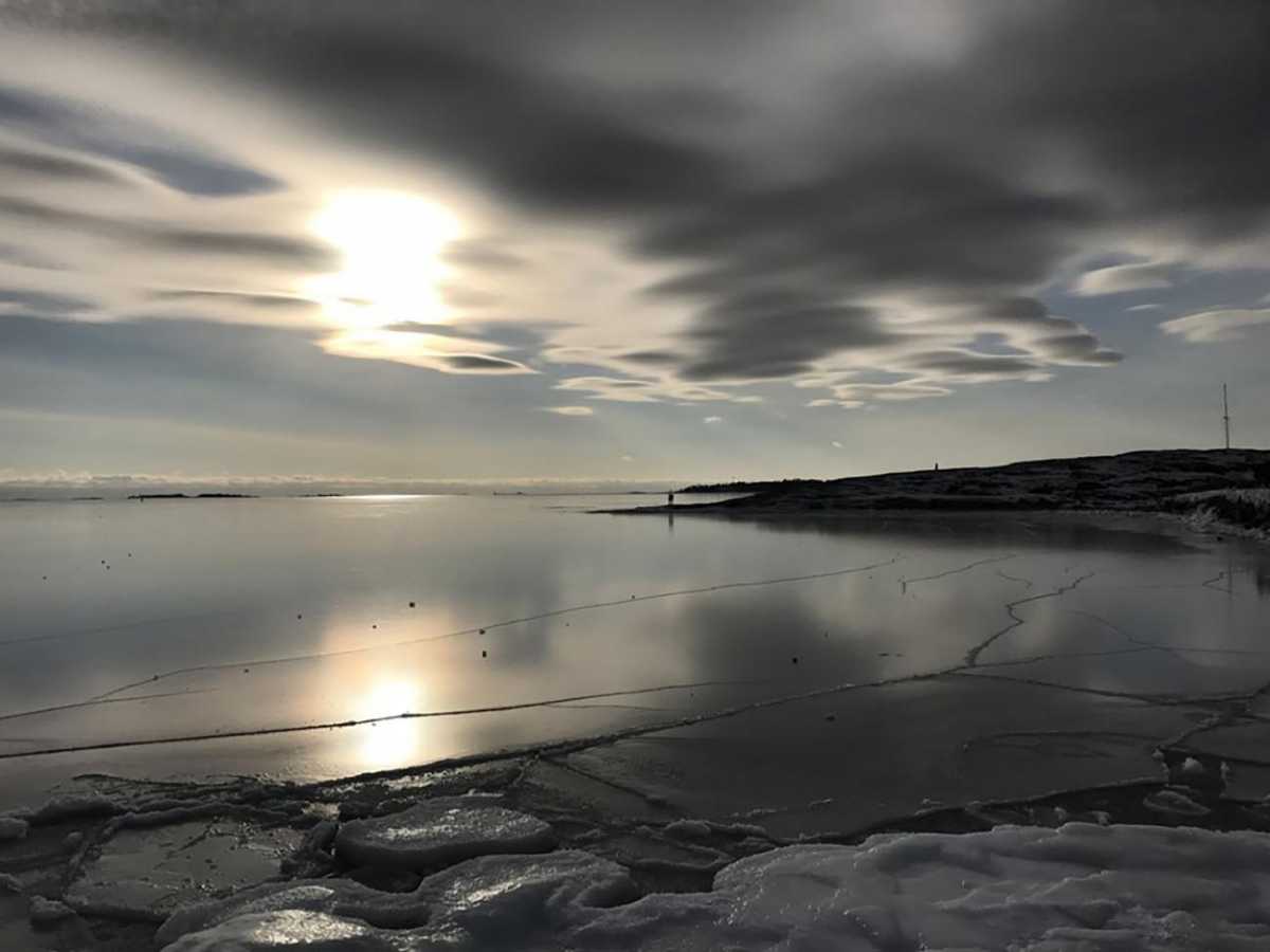 epa05788372 A couple (C) stands on the cliffs of an island at the frozen shoreline in Helsinki, Finland, 12 February 2017. Weather forecasts predict a turn to warmer temperatures from below zero, as a warm front approaches from Norway's coast and across Sweden.  EPA